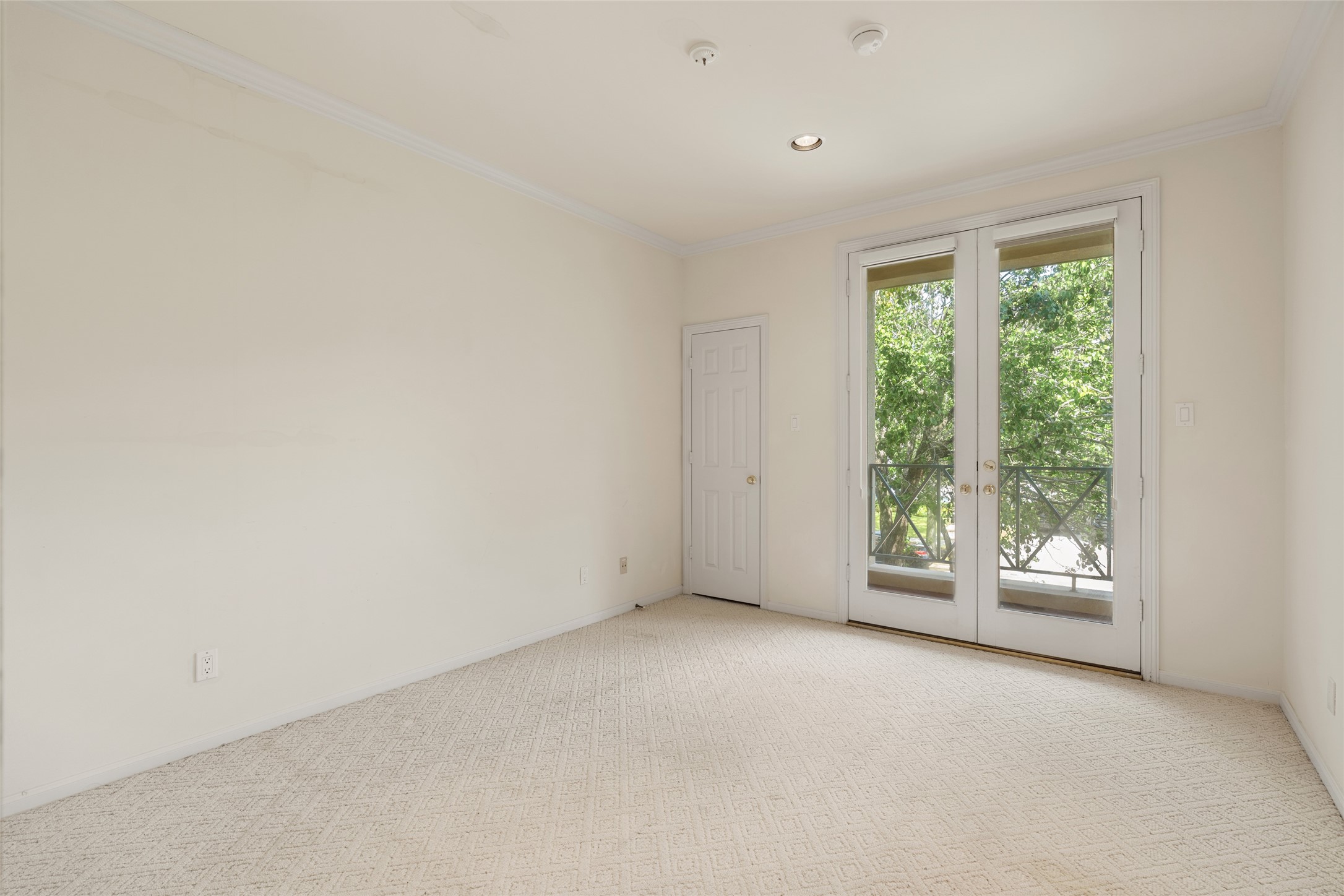 Bright and airy room featuring French doors that open to scenic views, complemented by soft carpeting and neutral walls.