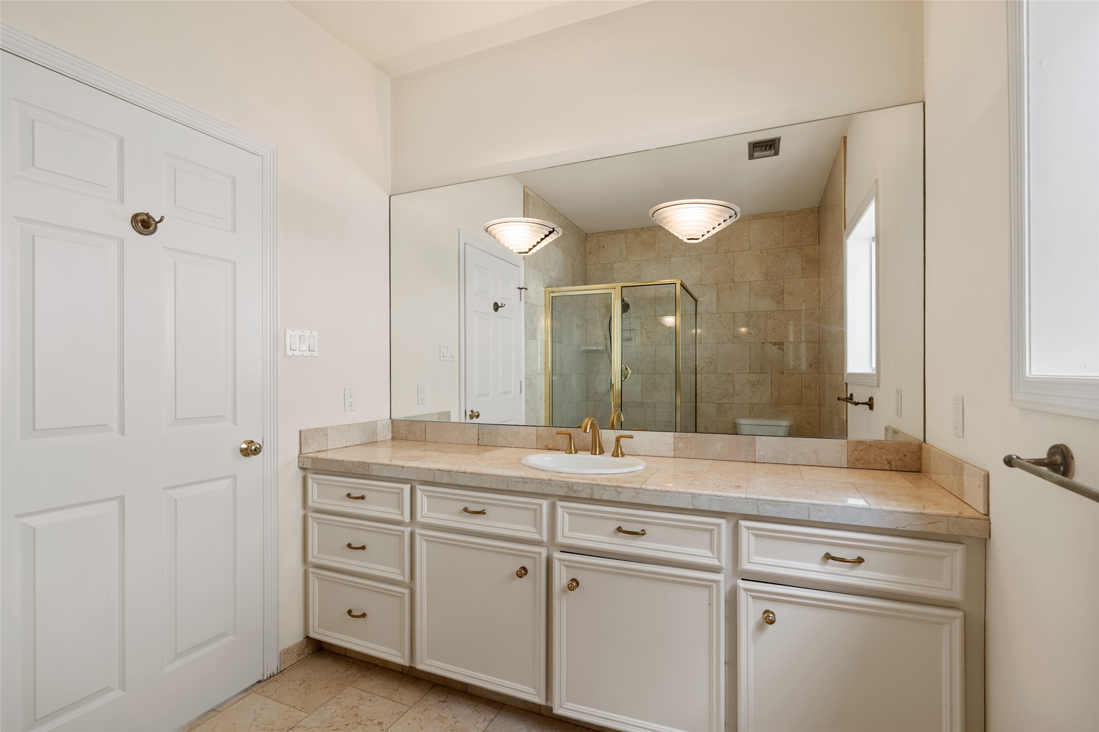 2nd primary bathroom featuring a spacious vanity with ample storage, a large mirror, and a luxurious glass-enclosed shower.