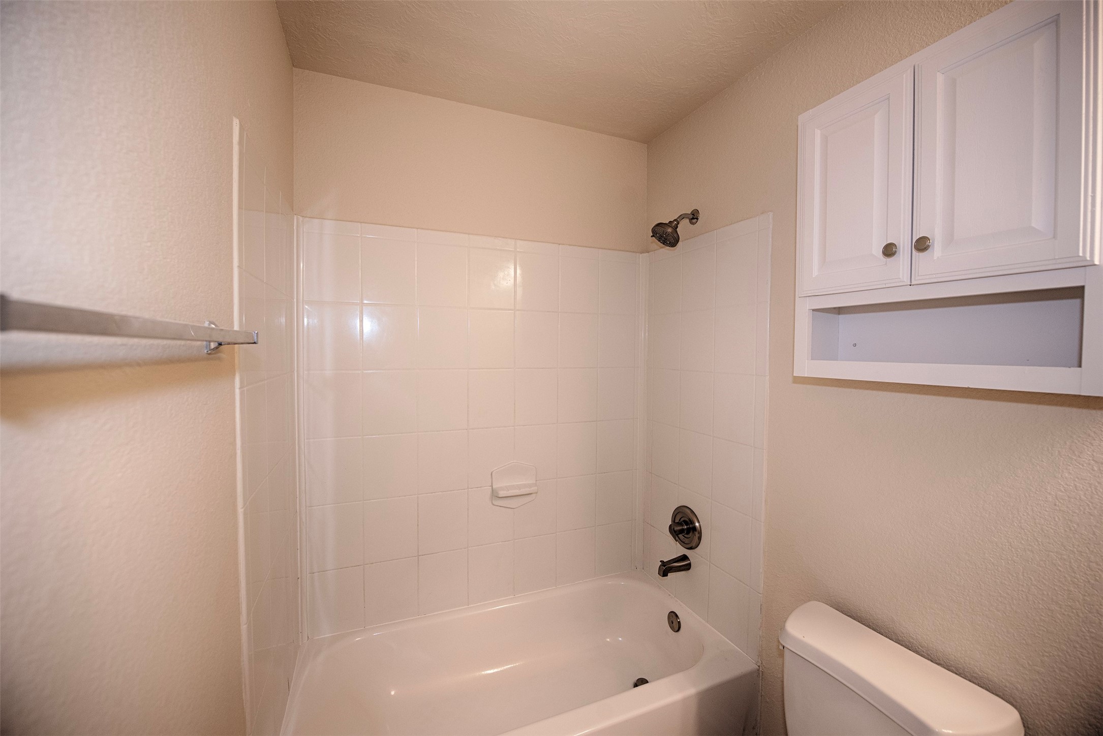 View of the bathroom showing the combo bath and shower as well as additional storage.