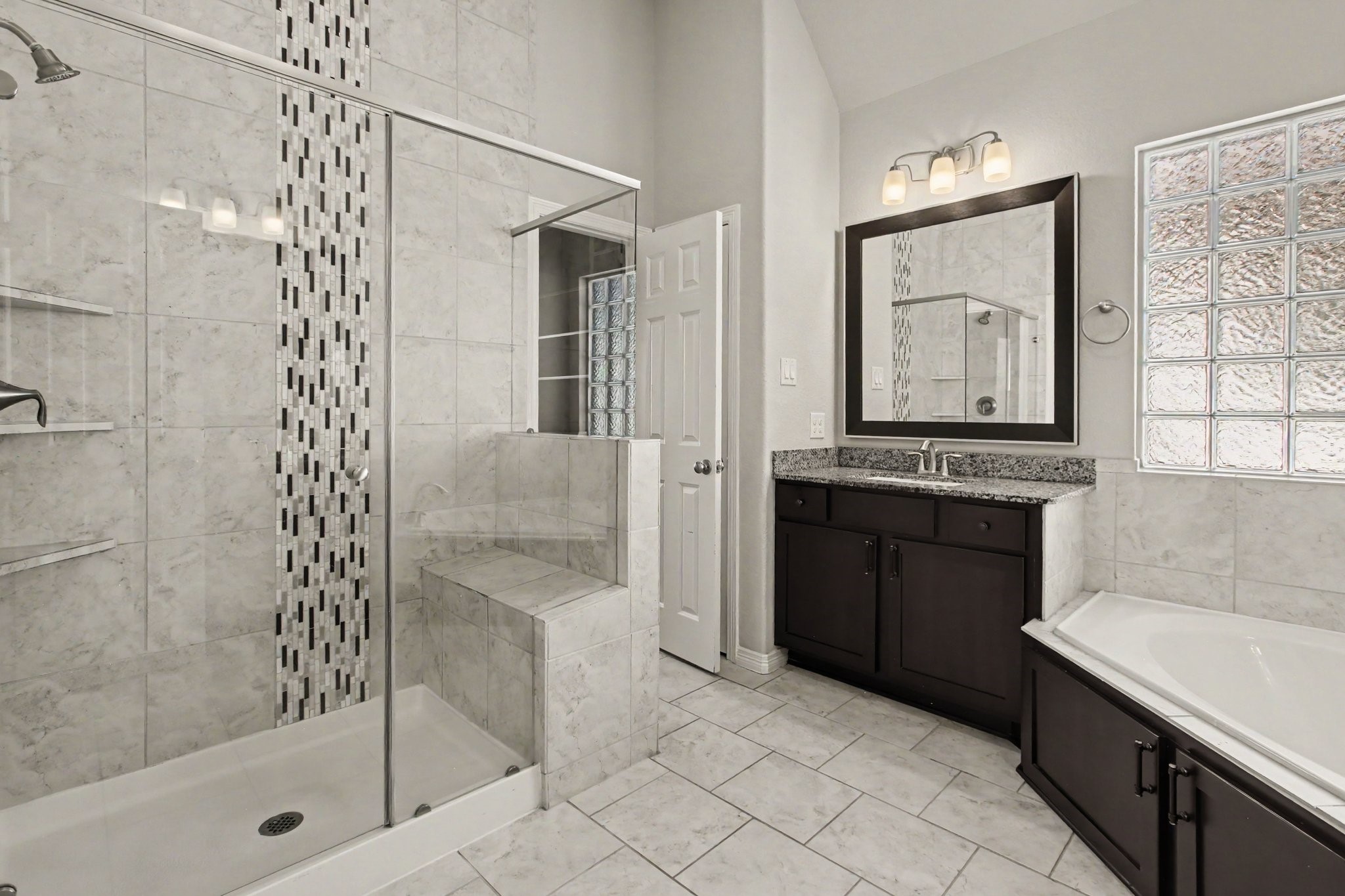 Primary bathroom with double vanities, bathtub and walk-in shower