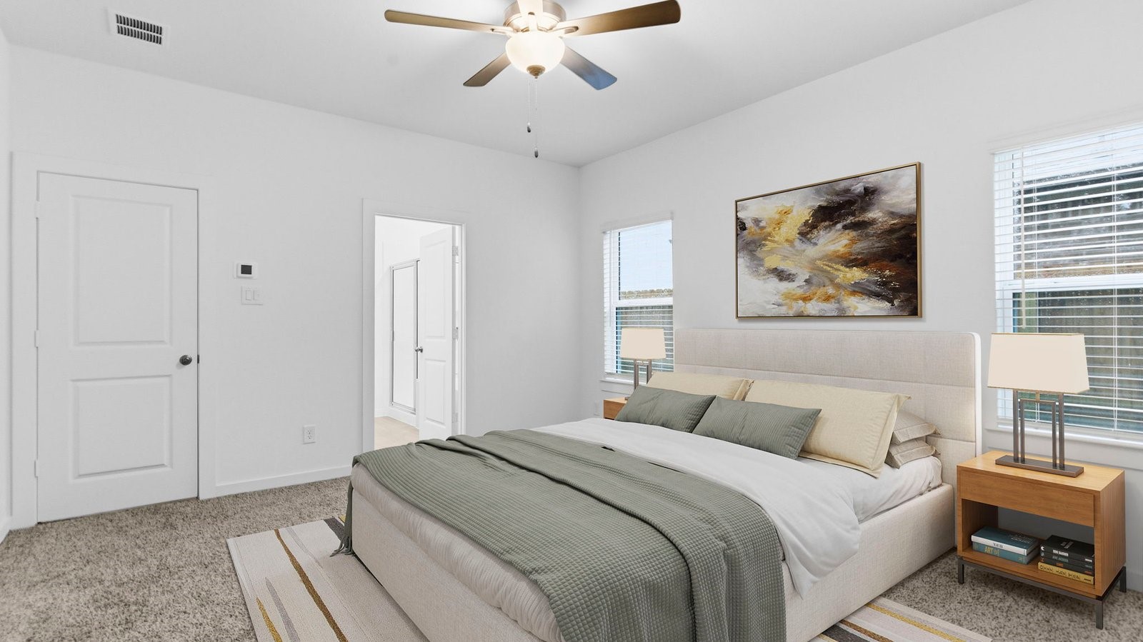 Primary bedroom with ceiling fan, plush carpeting, and a large walk-in closet.