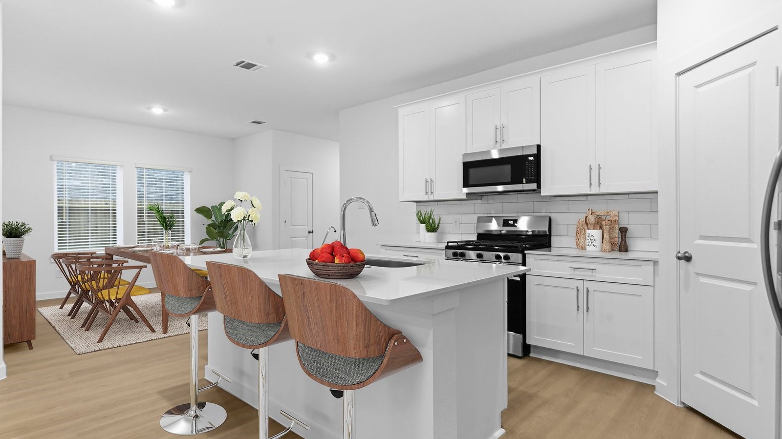 Bright and spacious kitchen with quartz countertops, stainless steel appliances, and an island with bar seating. Bright and spacious kitchen with quartz countertops, stainless steel appliances, and an island with bar seating.