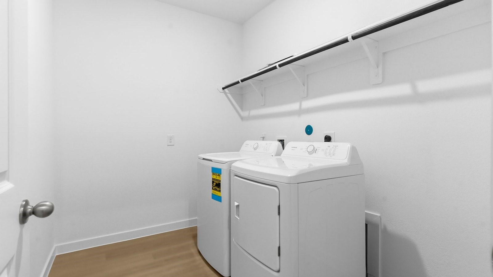 Spacious laundry room with washer and dryer connections, hanging rod, and vinyl wood flooring