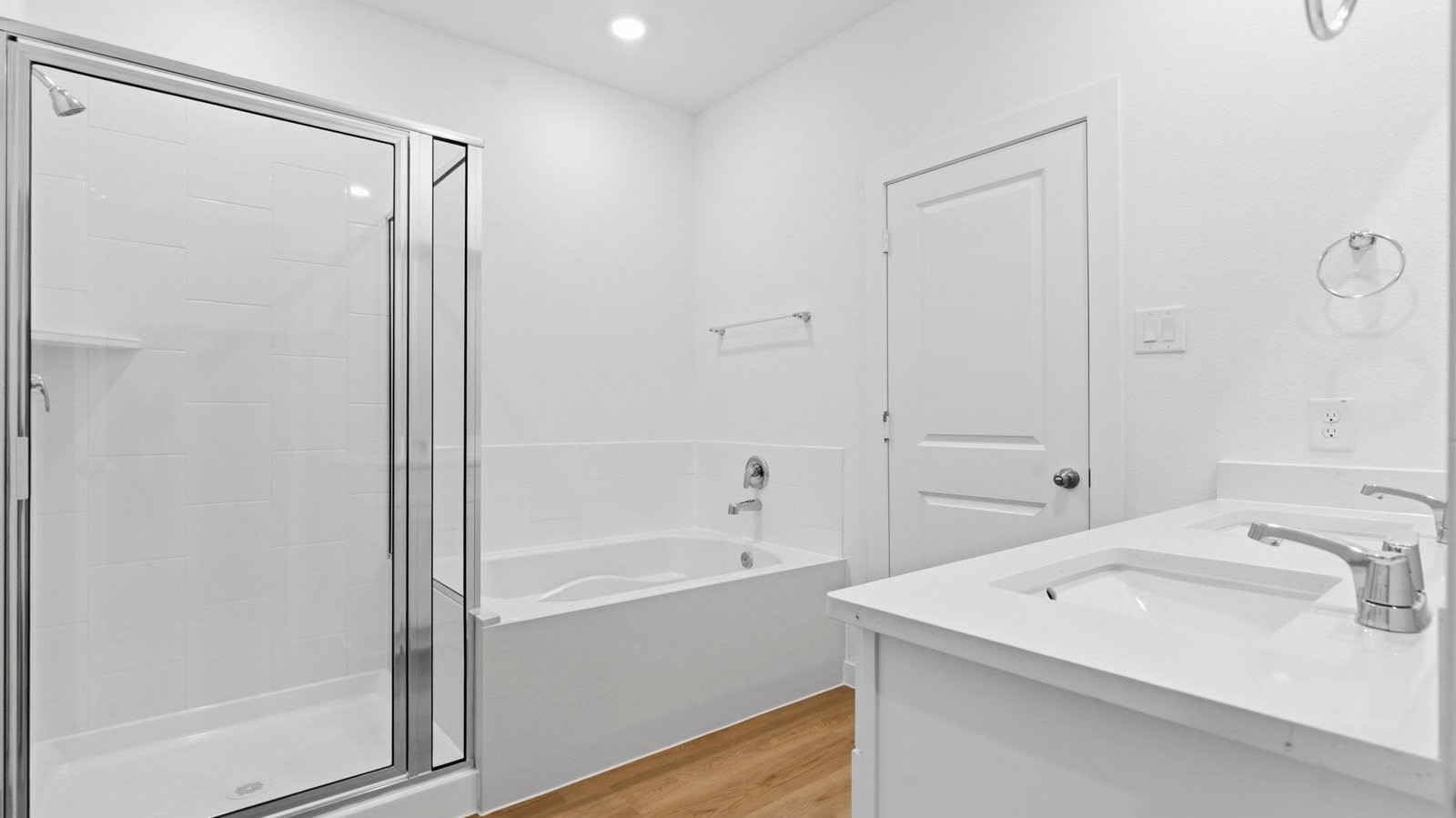 Modern primary bathroom with double vanities, quartz countertops, and a glass-enclosed shower with a walk-in closet.