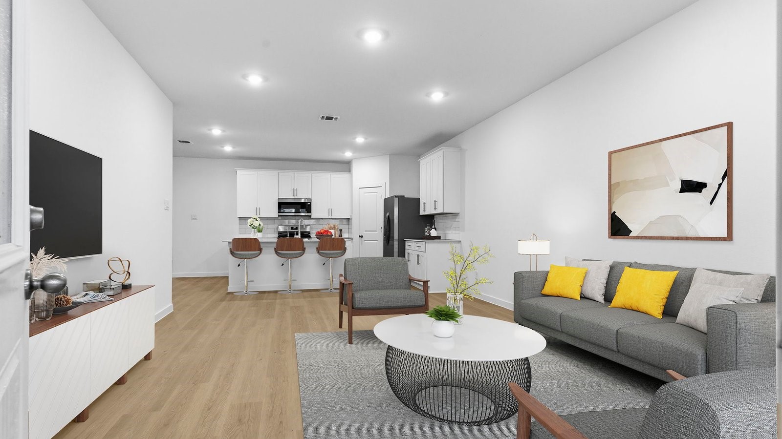 A cozy living room featuring large windows for natural lighting, vinyl wood flooring and a view to the kitchen and dining area.
