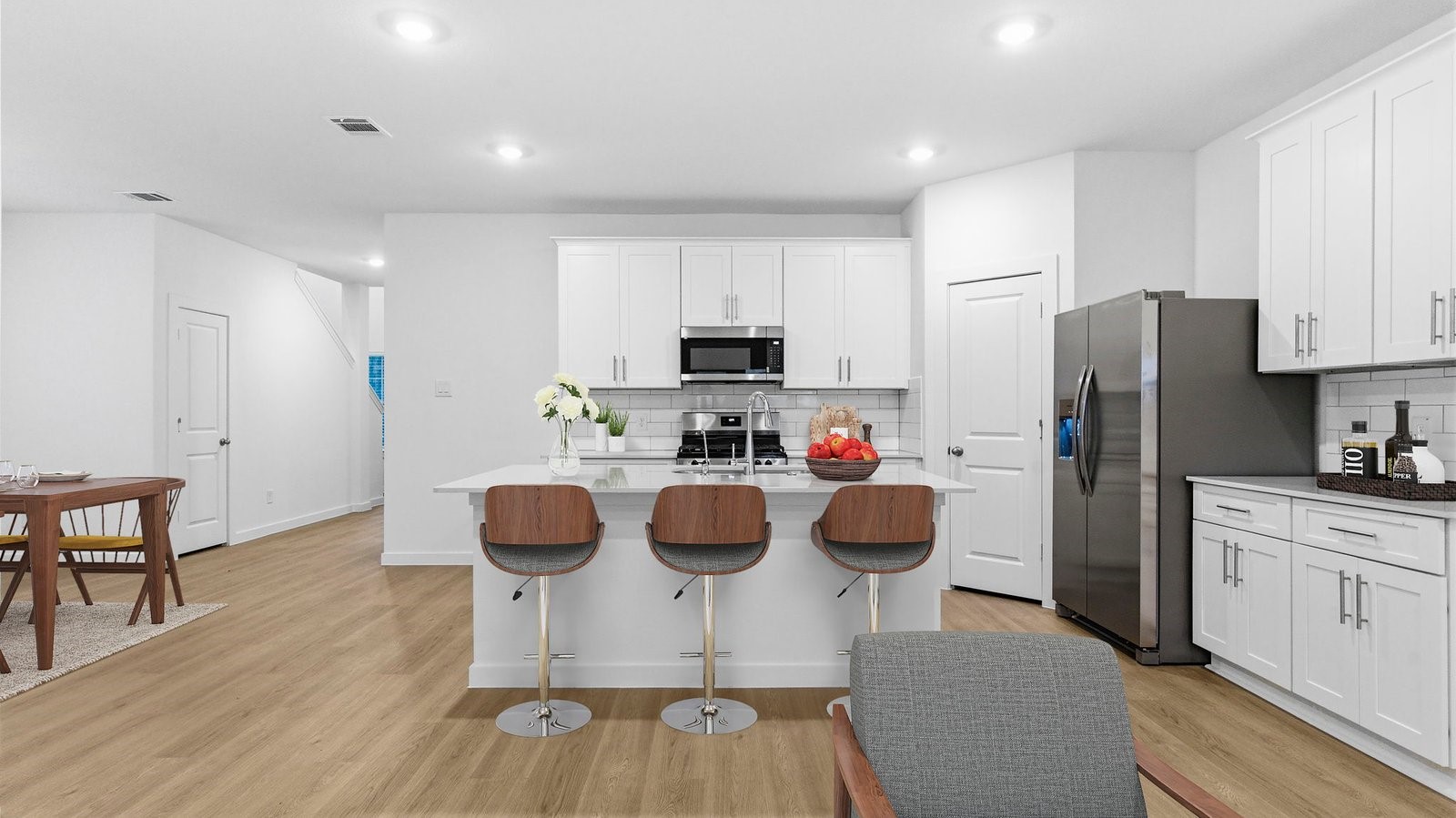 Bright and spacious kitchen with quartz countertops, stainless steel appliances, and an island with bar seating. Bright and spacious kitchen with quartz countertops, stainless steel appliances, and an island with bar seating.