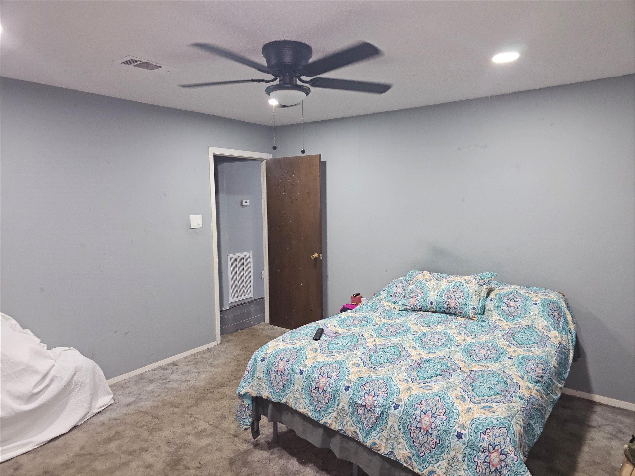 Spacious bedroom with soft carpeting, recessed lighting, ceiling fan, and neutral paint.