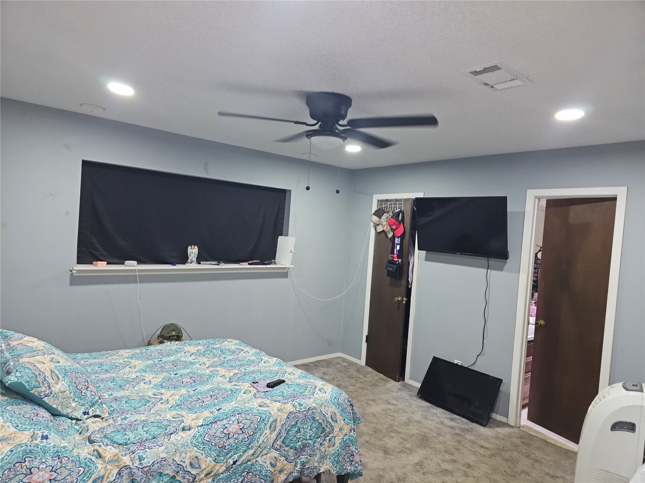 Large primary bedroom features soft carpeting, recessed lighting, ceiling fan, and an ensuite.