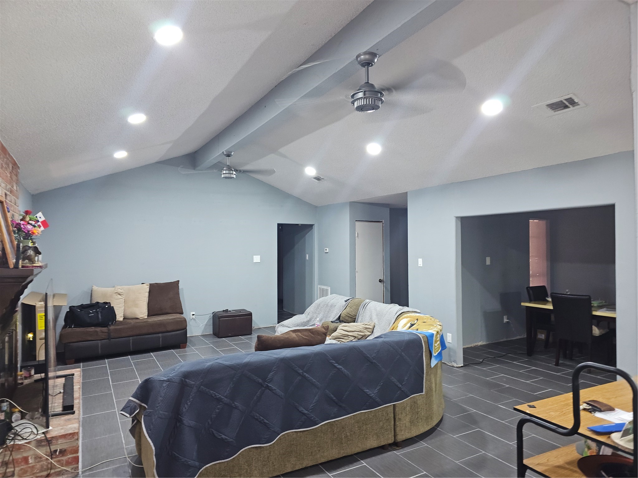 Spacious living room features vaulted ceilings, recessed lighting, ceiling fans, and durable tile flooring.
