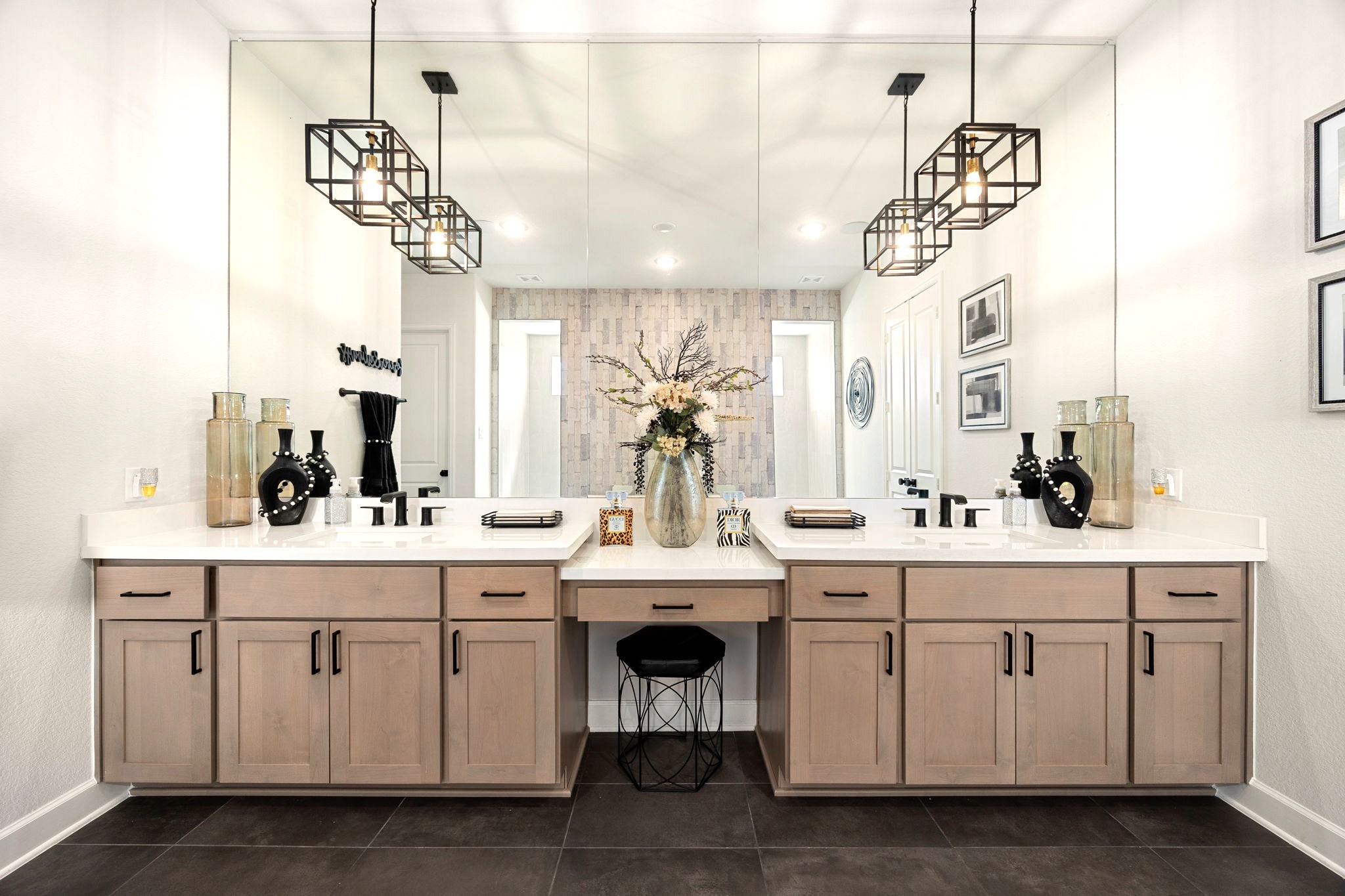 A custom vanity area showcases premium quartz countertops, thoughtfully designed drawers and cabinets for storage, and upgraded black faucets and pendant lighting that add a bold, contemporary contrast to the luxurious finishes.