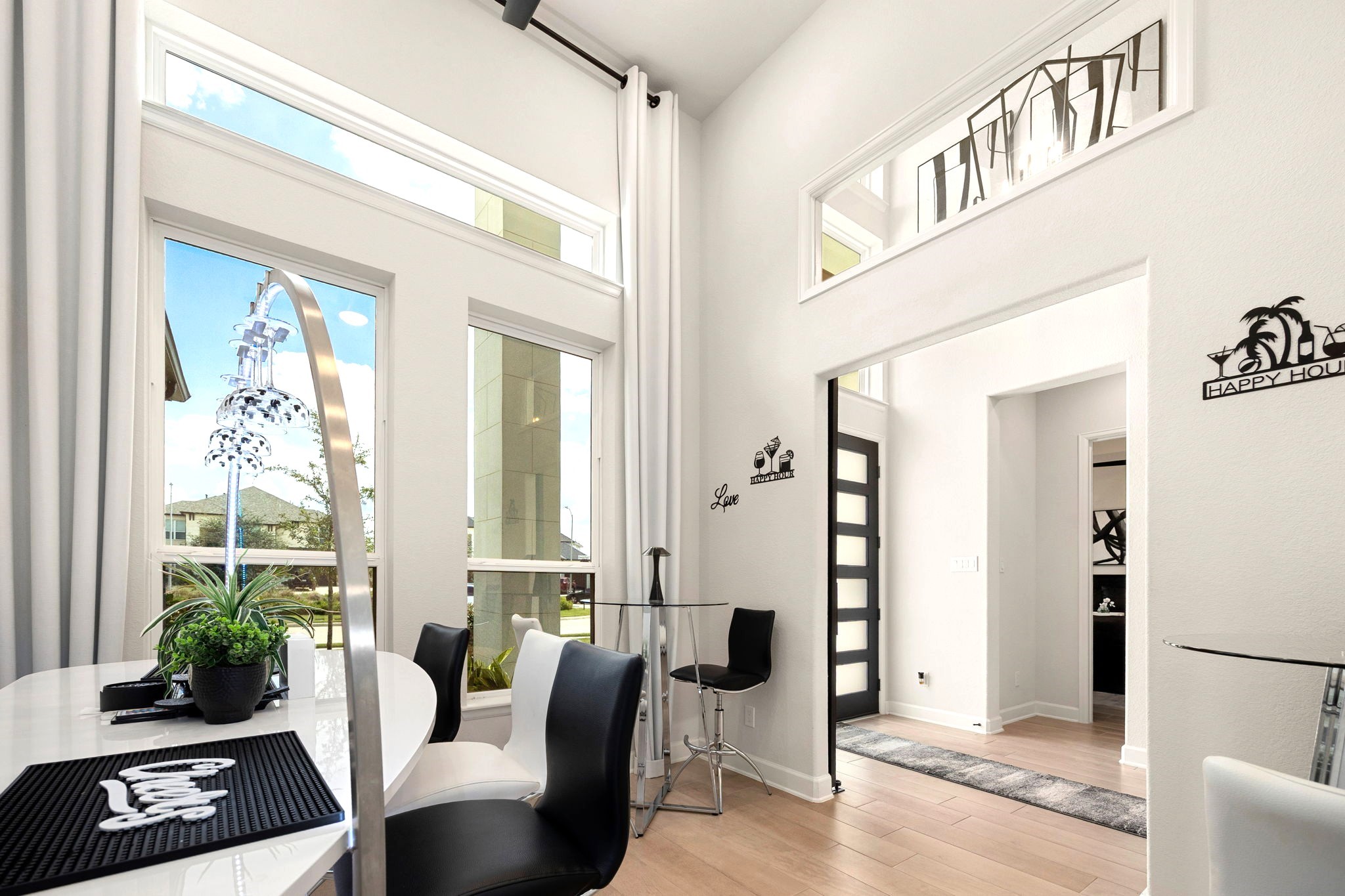 A sophisticated front-facing private office features soaring ceilings, striking vertical and horizontal windows that invite natural light, and a custom sliding barn door, creating an elegant and functional workspace with added privacy.