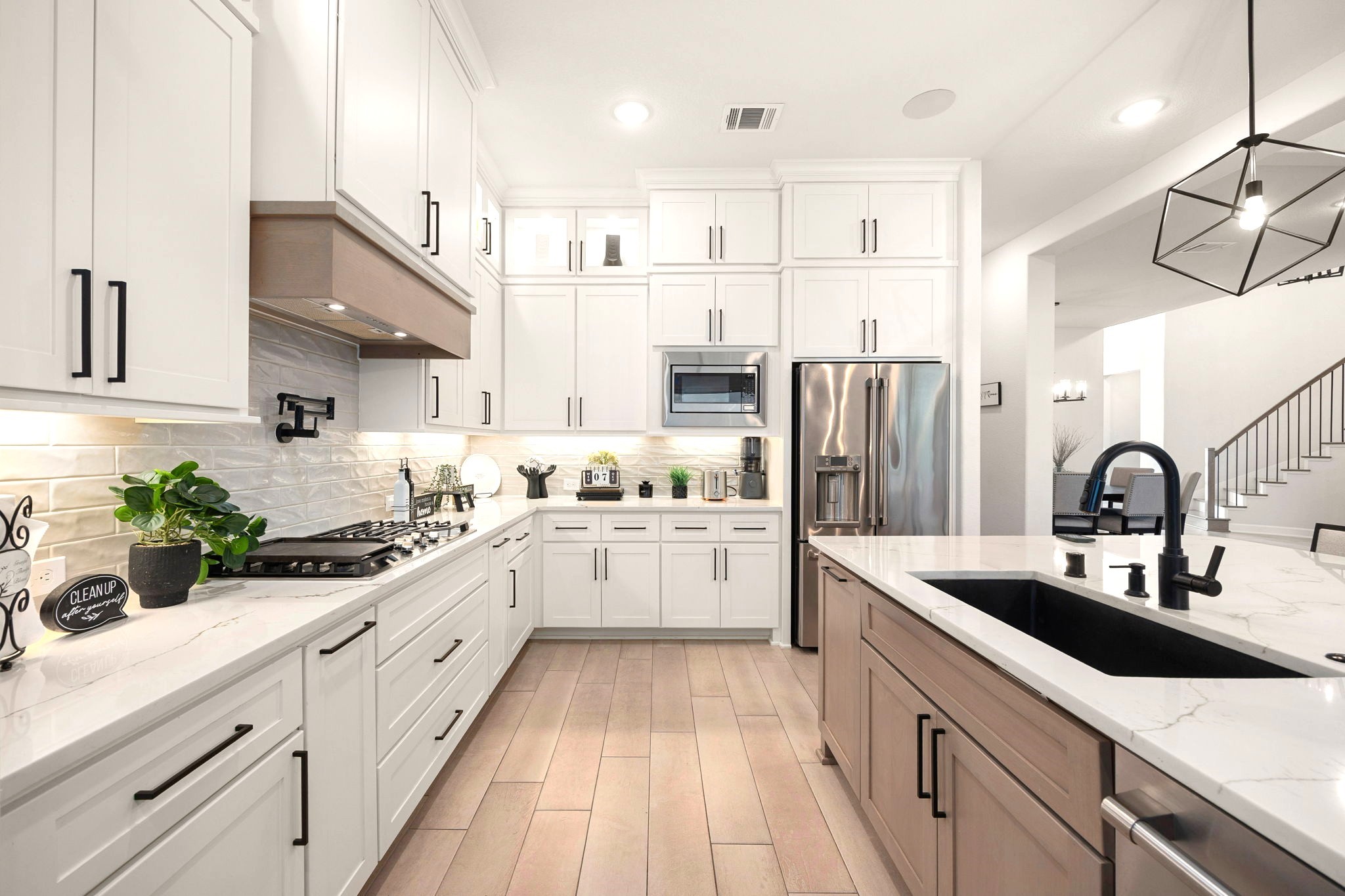A chef-inspired kitchen showcases an upgraded vented range hood, convenient pot filler above the cooktop, and a sophisticated black stone sink, combining premium finishes with thoughtful functionality for elevated everyday living and entertaining.