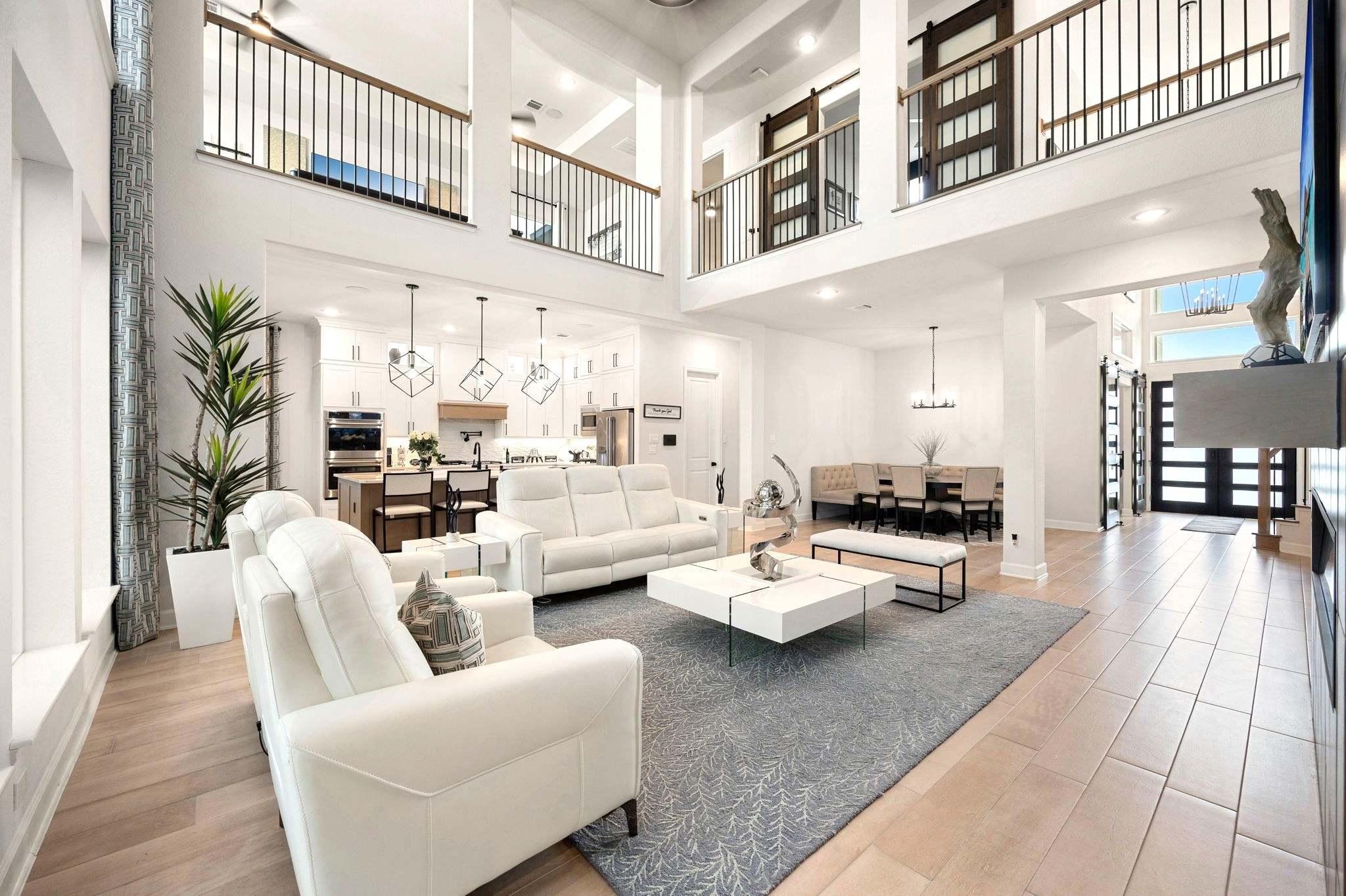 An expansive view of the first-floor living, dining, and kitchen areas showcases the home's open-concept design, creating an elegant flow between everyday living and sophisticated entertaining beneath soaring ceilings and surrounded by beautiful architectural details