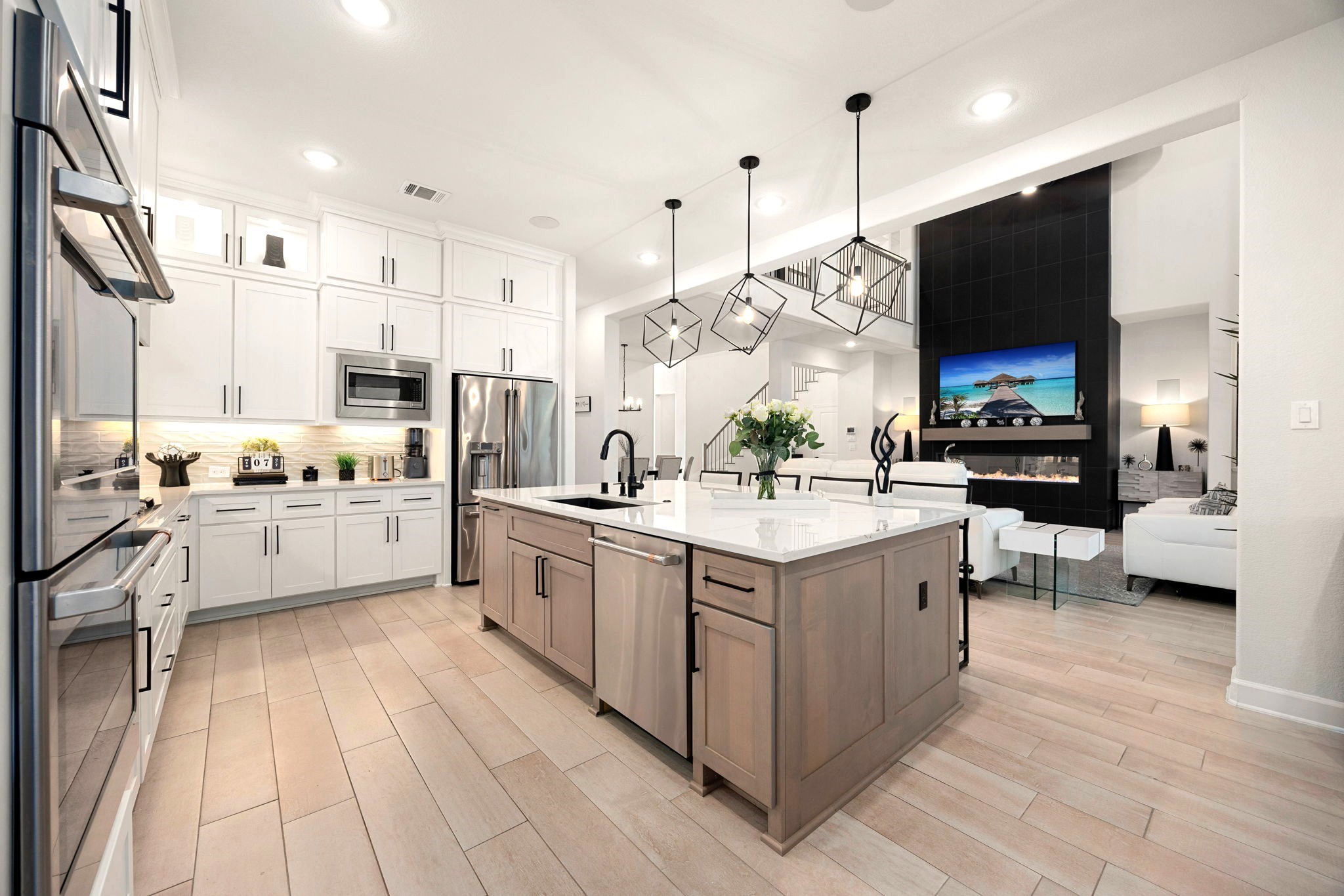 Elegant upper cabinetry with accent lighting, under-cabinet illumination, and stylish pendant lights above the oversized island create a beautifully layered kitchen ambiance that blends modern sophistication with functional luxury.