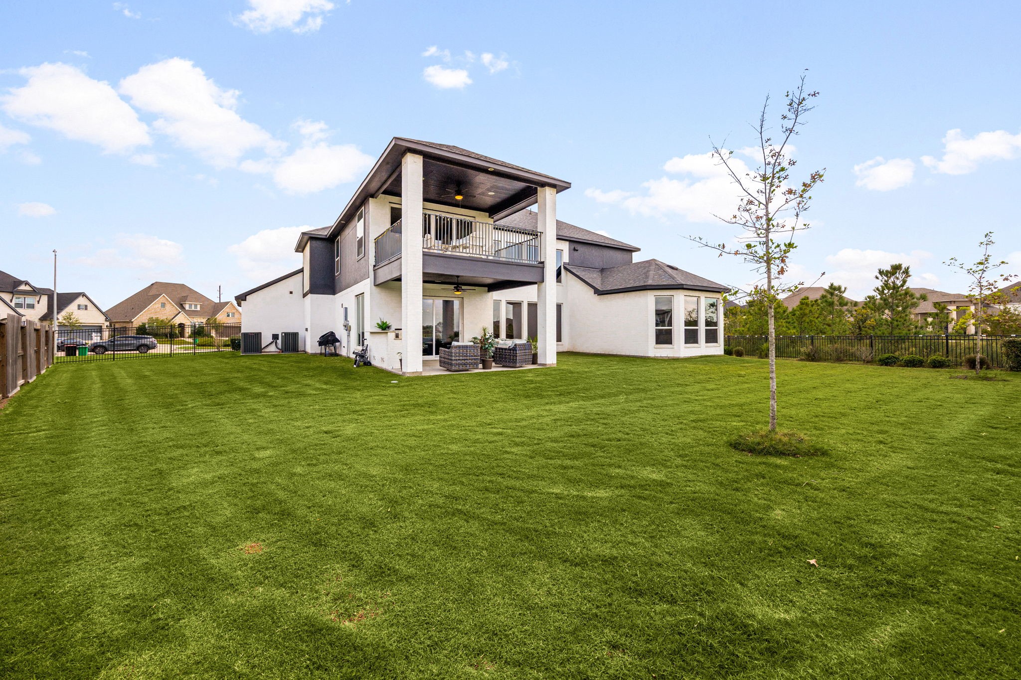 A picturesque backyard view highlights the home's striking brick exterior, expansive covered patios, and additional usable side-yard space offering endless possibilities for future outdoor enhancements, recreation, or personalized landscaping.