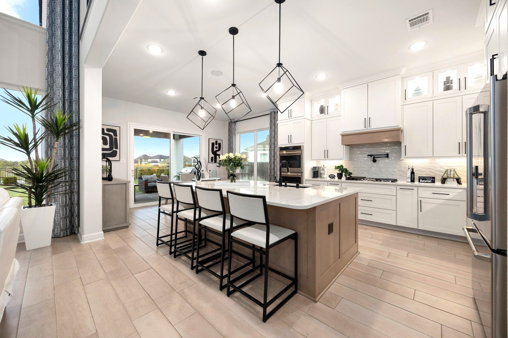 A chef-inspired cooking station features a convenient pot filler, double ovens, deep pots-and-pans drawers beneath the cooktop, upper cabinets with lighting, and a pull-out spice rack, delivering exceptional functionality and upgraded convenience in this beautifully appointed luxury kitchen.