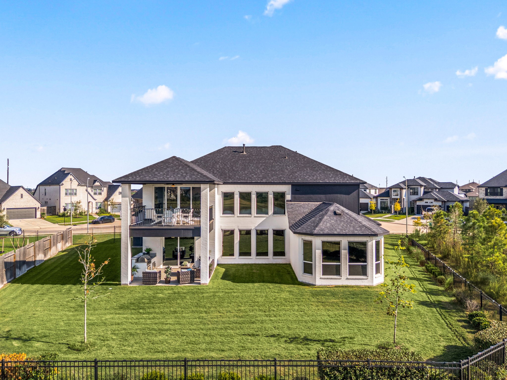 A stunning aerial view showcases the expansive backyard and both covered outdoor living patios, thoughtfully positioned on the first and second floors to maximize lake views and create exceptional spaces for outdoor entertaining and relaxation.