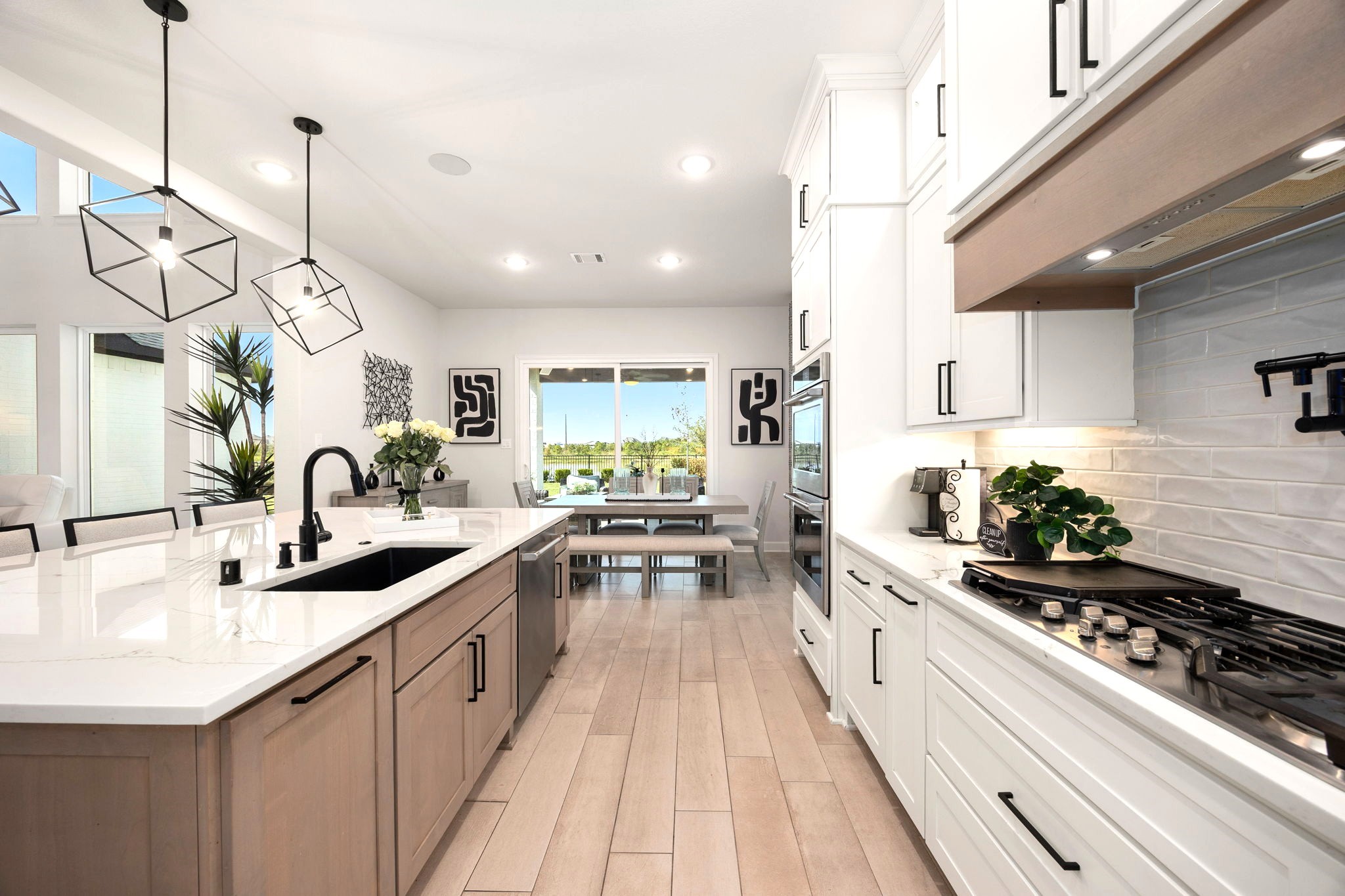 An inviting view from the kitchen showcases the dining areas expansive sliding glass doors, creating a seamless connection to the covered outdoor patio and offering the perfect setting for effortless indoor-outdoor living, dining, and entertaining.