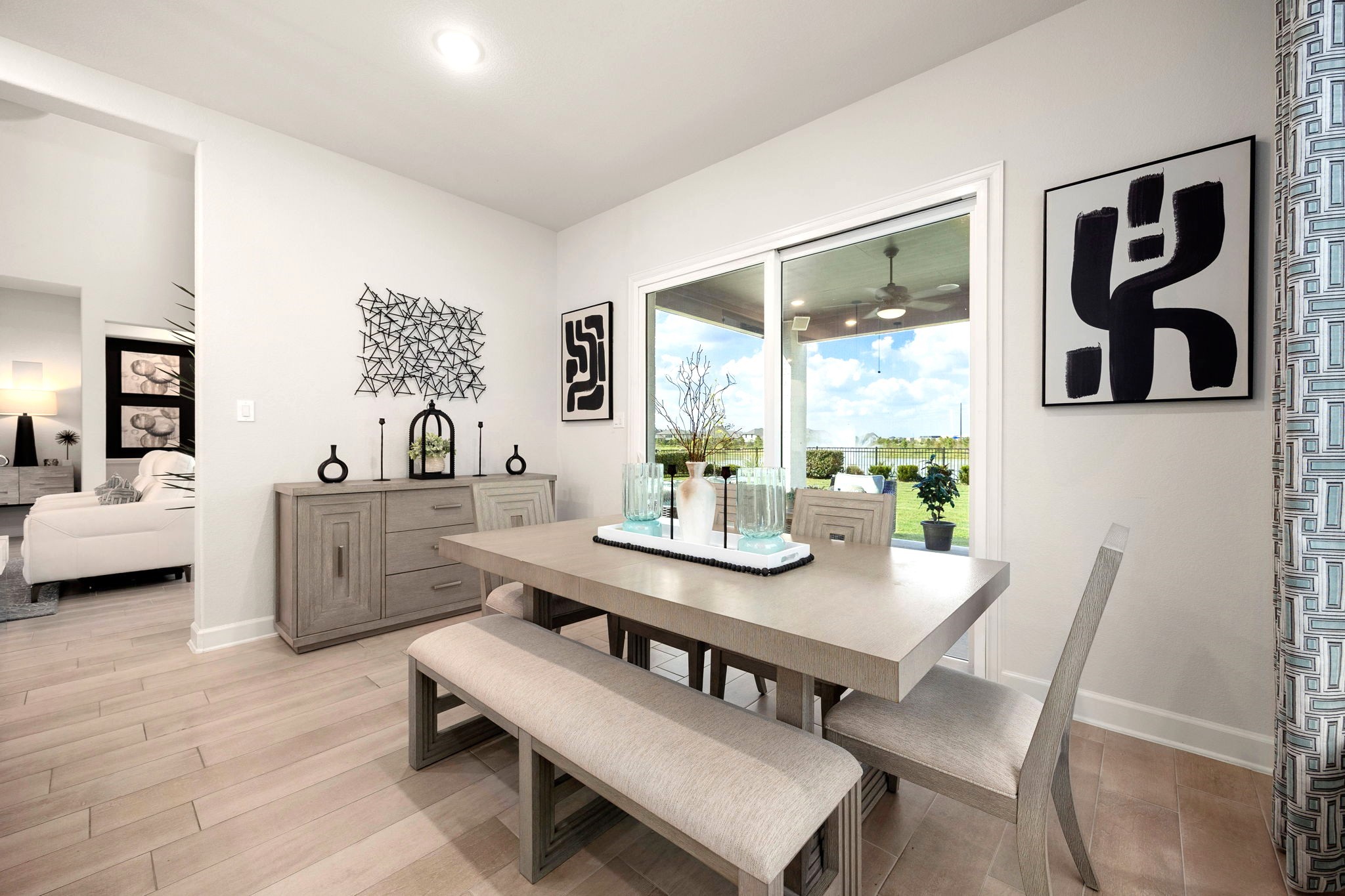 A spacious dining area features expansive sliding glass doors opening to a covered patio with an outdoor kitchen, creating an inviting indoor-outdoor setting perfect for elegant dinners, casual gatherings, and effortless entertaining.