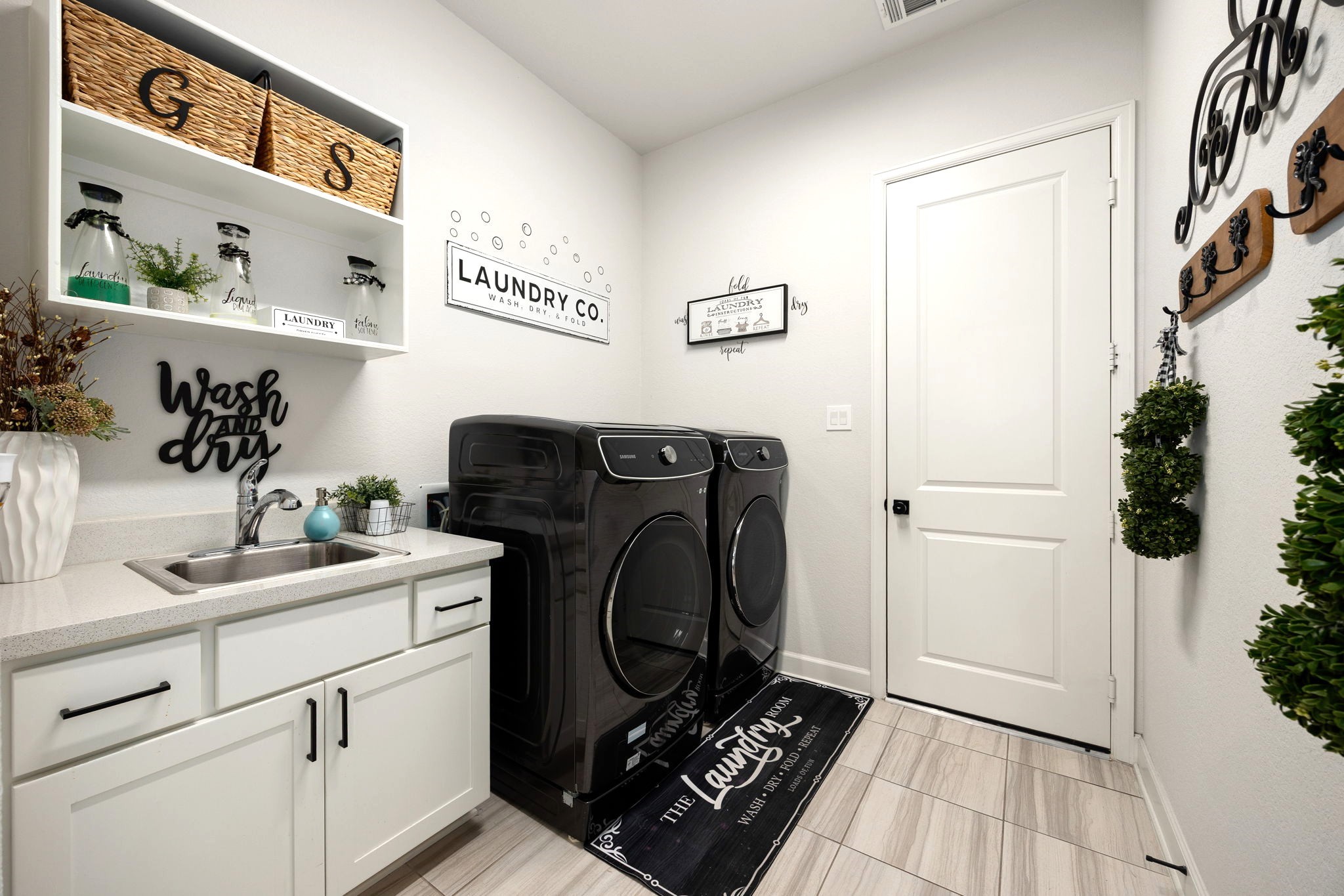 An expansive laundry room features a custom-added sink, upgraded cabinetry, and drawers for exceptional storage and functionality, with convenient direct access to the impressive four-car garage for everyday ease and organization.