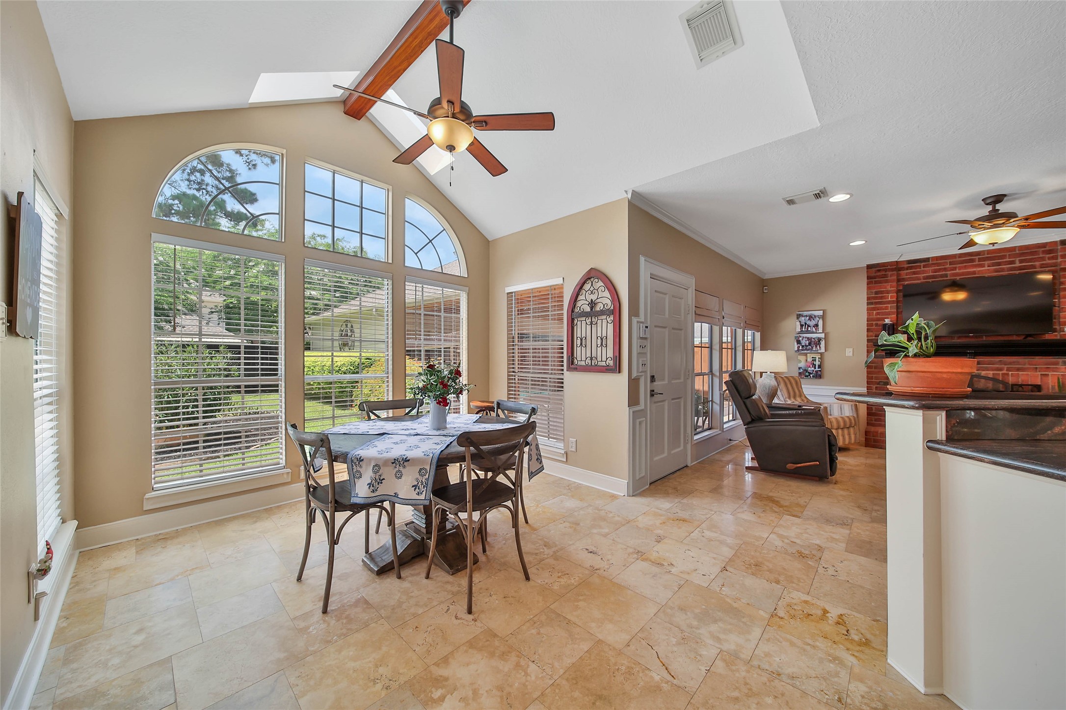 Vaulted breakfast room with dramatic arched windows, skylights and views toward the backyard pool.