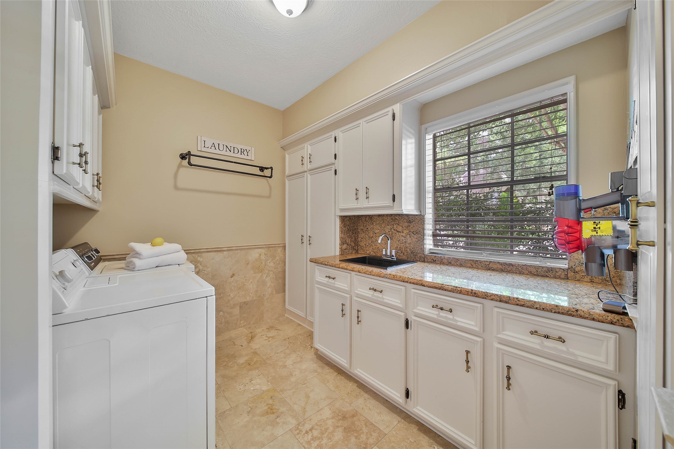 Oversized utility room provides substantial cabinetry, counter space and utility sink.
