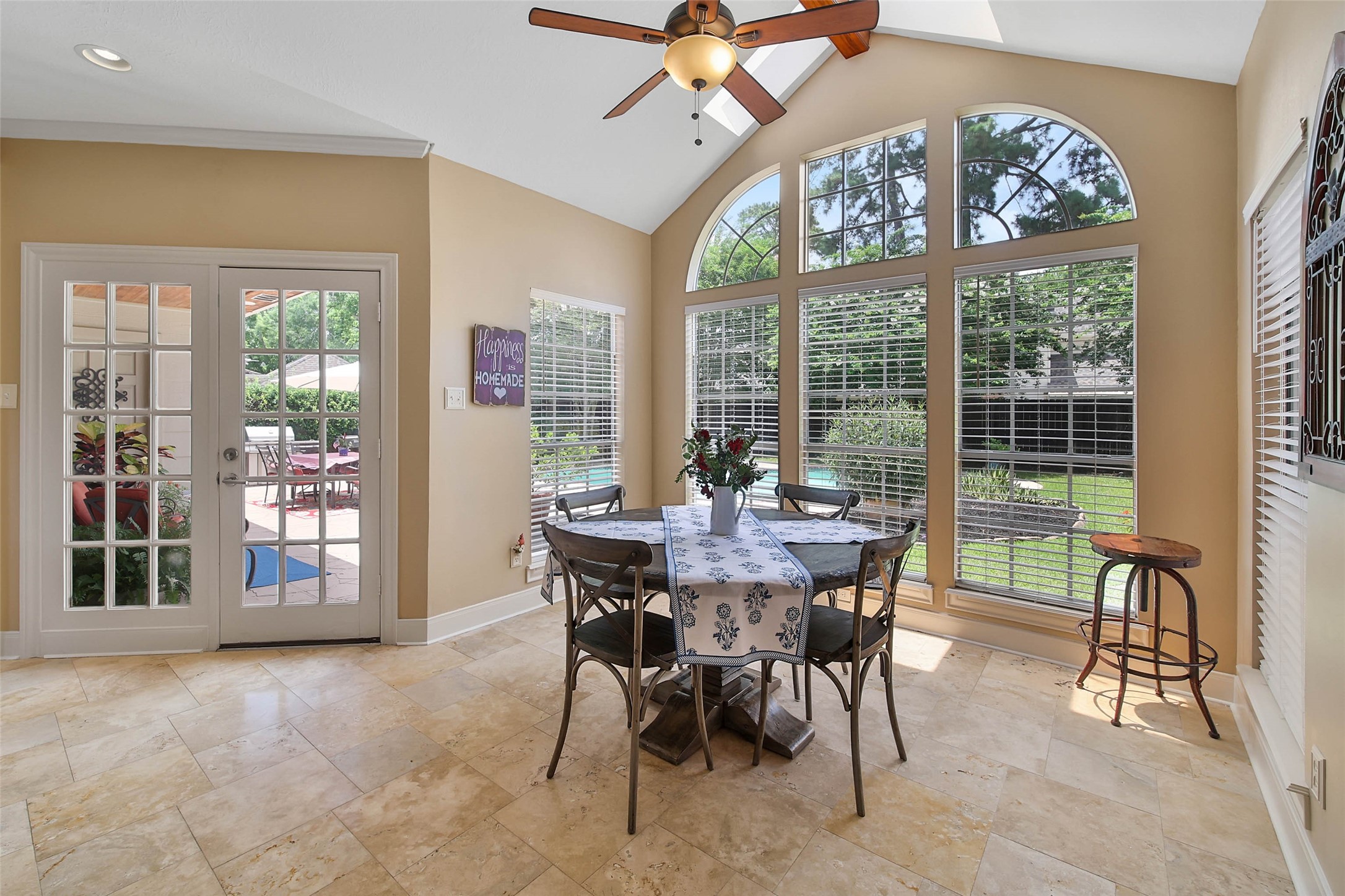 A dramatic wall of windows and vaulted ceiling bring natural light into the breakfast area while connecting the interior to the pool and backyard.
