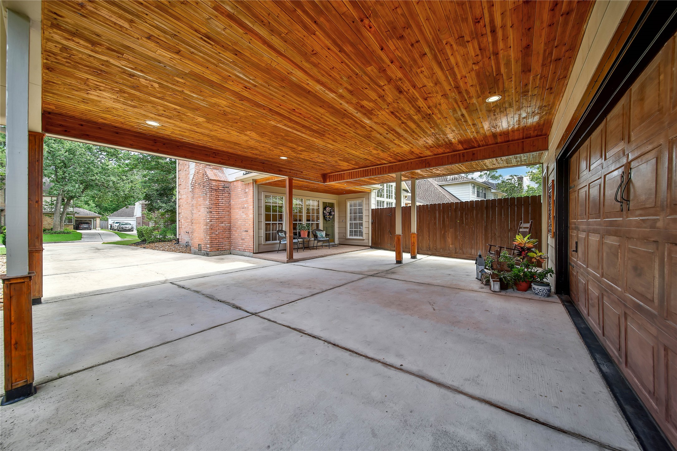 The cedar tongue-and-groove ceiling makes it feel intentional rather than simply like covered parking. This is a party pavilion that also happens to be a porte-cochere.