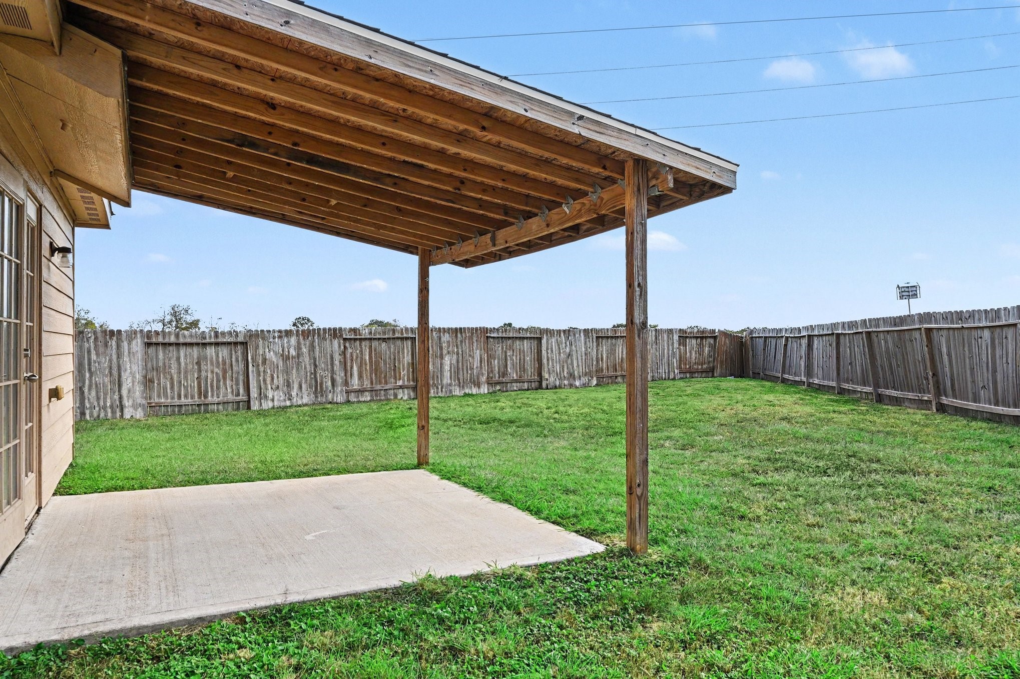Spacious backyard with covered patio and plenty of open green space for gardening or entertaining.