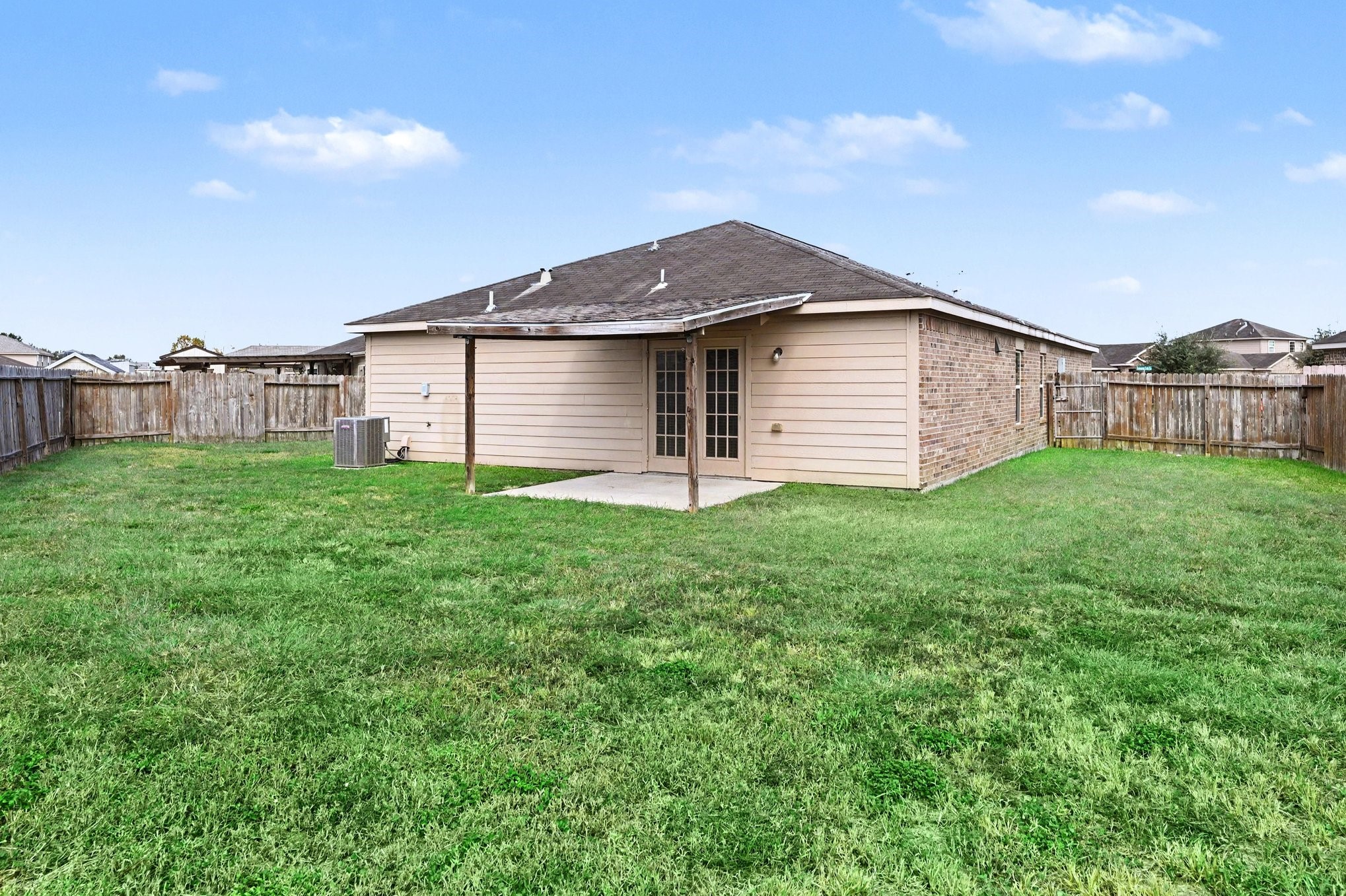 Spacious backyard with covered patio and plenty of open green space for gardening or entertaining.
