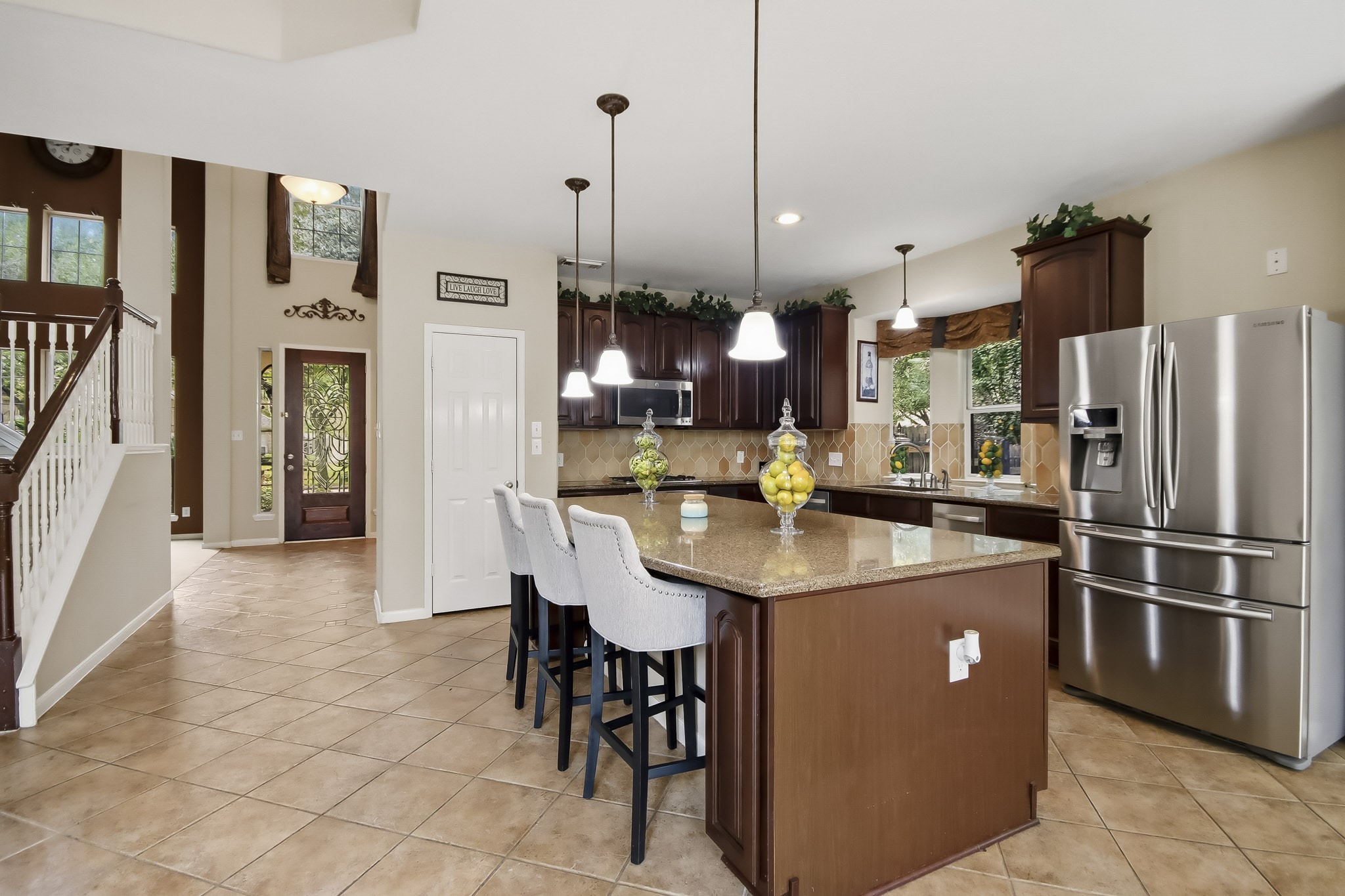 Beautiful open-concept kitchen featuring granite countertops, elegant pendant lighting, and a spacious island perfect for gathering and entertaining. Refrigerator and three bar stools included with the sale of the home!