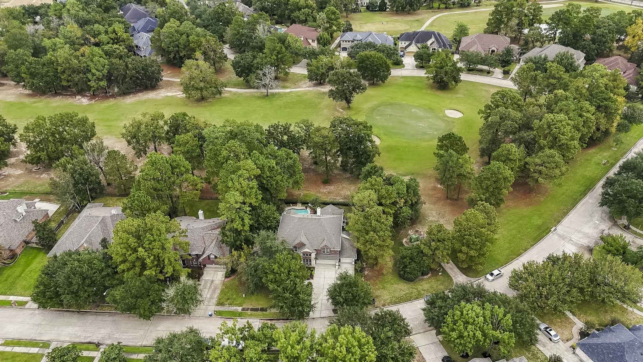 Another stunning birds-eye view showcasing the homes prime location overlooking the 10th hole of the golf course, surrounded by lush greenery and mature trees.
