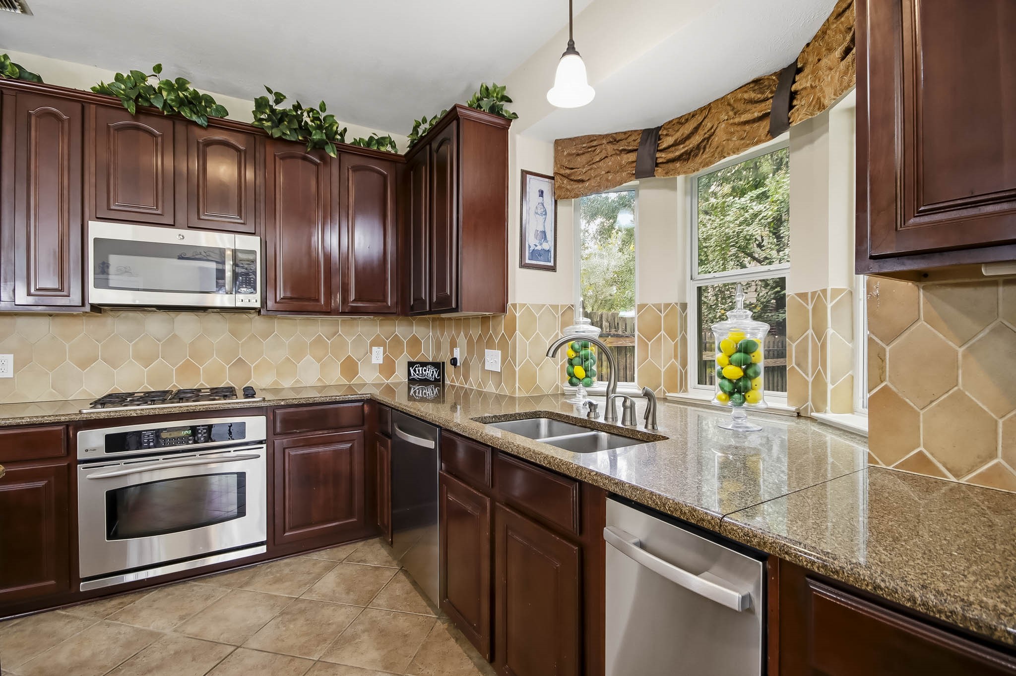 Beautiful kitchen featuring granite countertops, stainless steel appliances, and a charming window above the sink offering gorgeous outdoor views and abundant natural light.