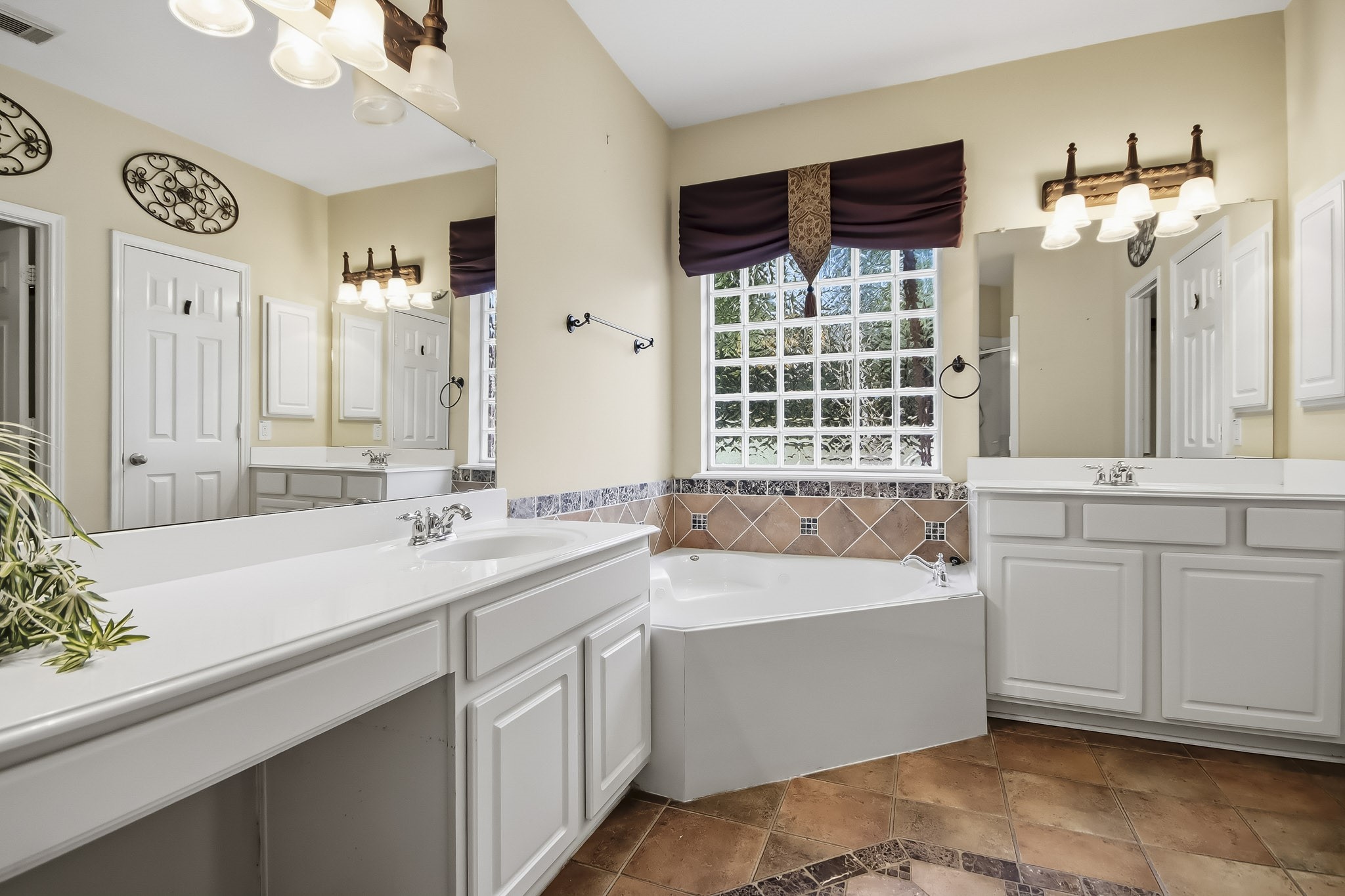 Spacious primary bathroom featuring a relaxing soaking tub and generously spaced vanities, offering plenty of countertop space, storage, and comfort for your daily routine.