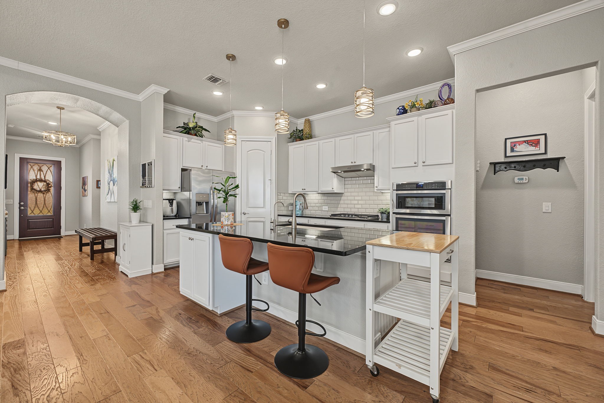 Large center island with sink and barstool seating. Note the width between the Kitchen and Family Room which is not visible here.