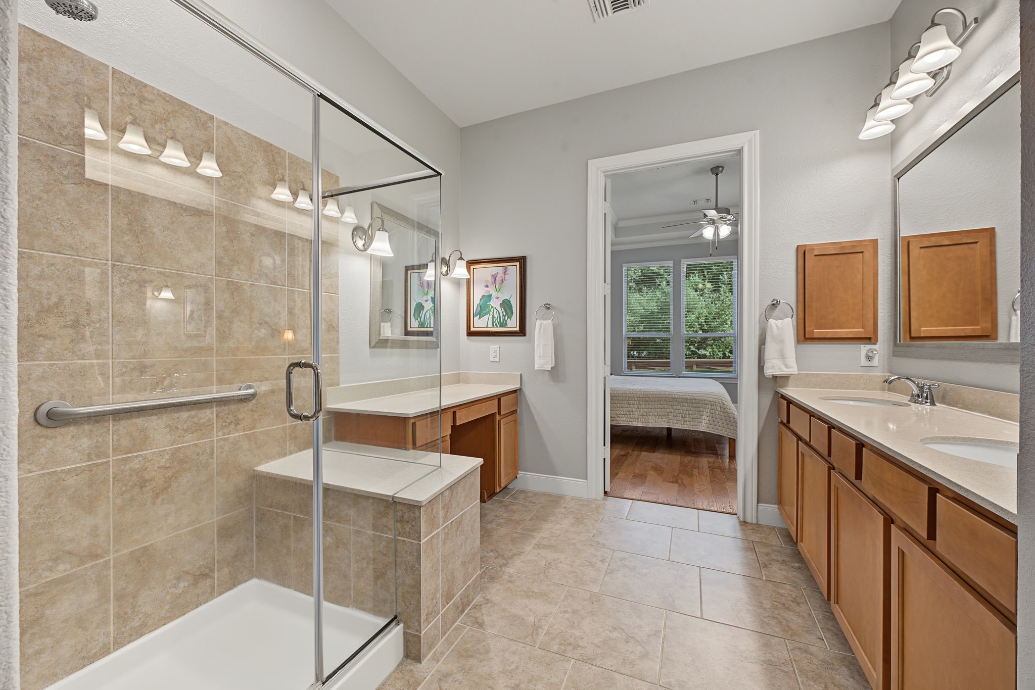 Larger shower with seating bench and safety rail inside.