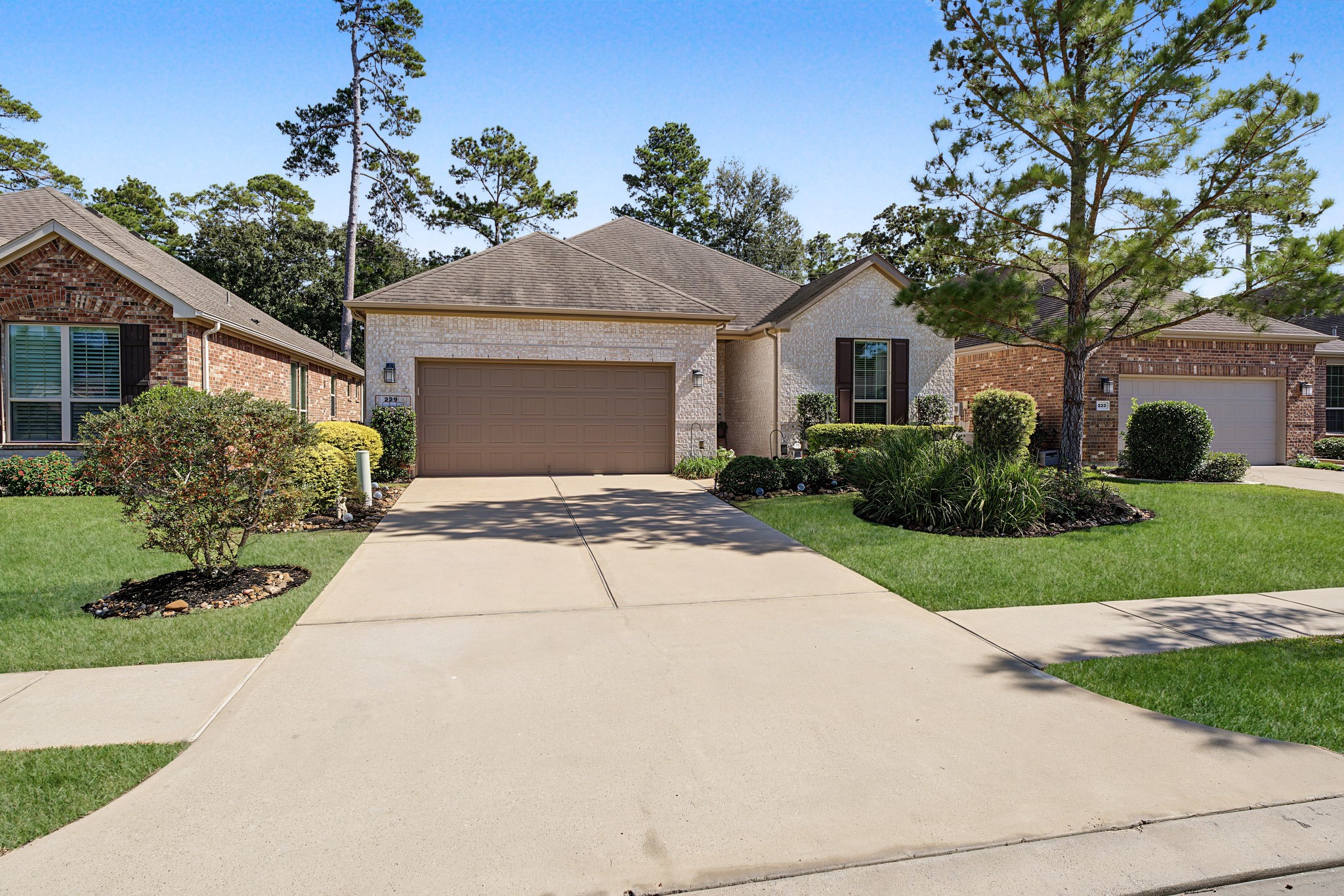 Long, double-wide driveway leading to the attached garage. Sidewalk community inside the gates.