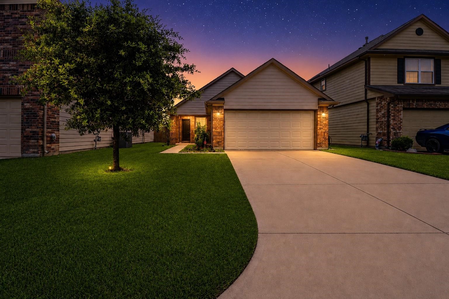 Charming single-story home with a well-maintained lawn and illuminated walkway. Features a spacious driveway leading to a two-car garage. Ideal for comfortable living in a peaceful neighborhood setting.
