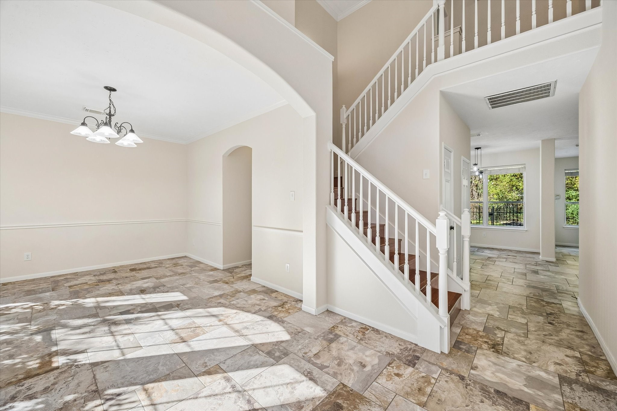 This view of the entry is perfect! The open staircase and arched doorway add architectural charm, while the open layout creates a natural flow throughout the home.