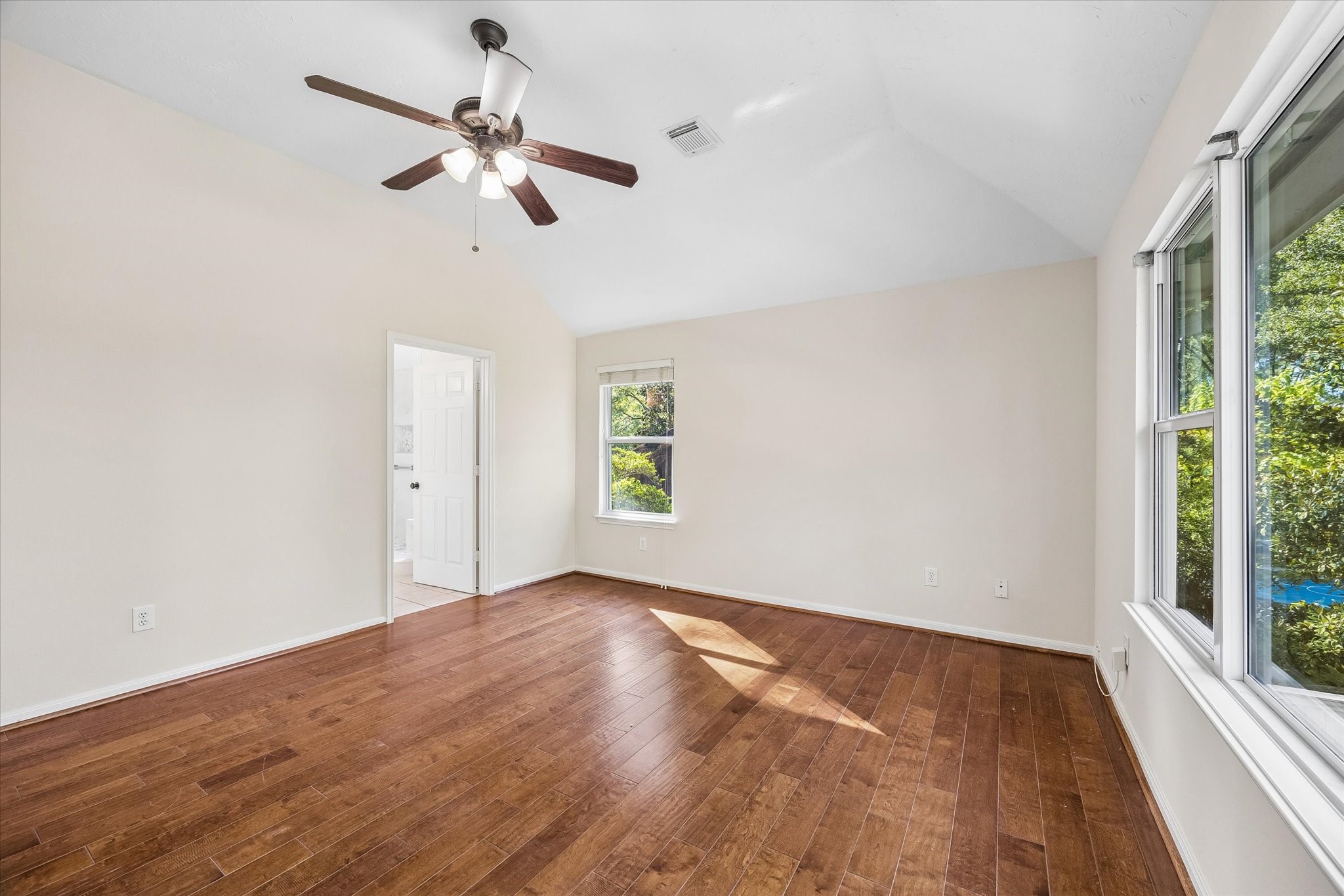 Another view of the second-level primary suite showcasing the vaulted ceilings The en-suite bathroom adds convenience to this spacious retreat.