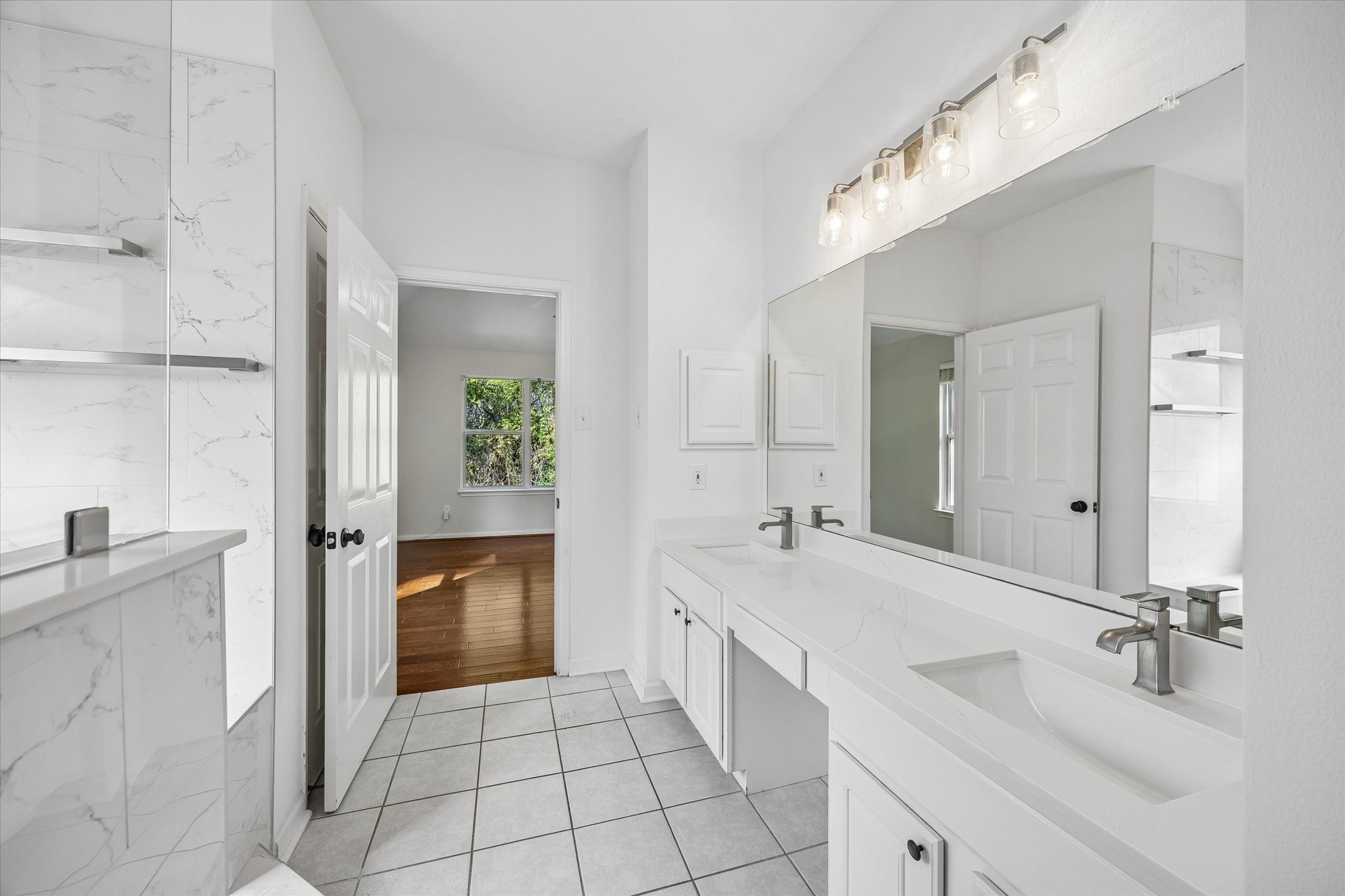 Another view of the primary en-suite bathroom, where the designer lighting adds the perfect finishing touch to this space.