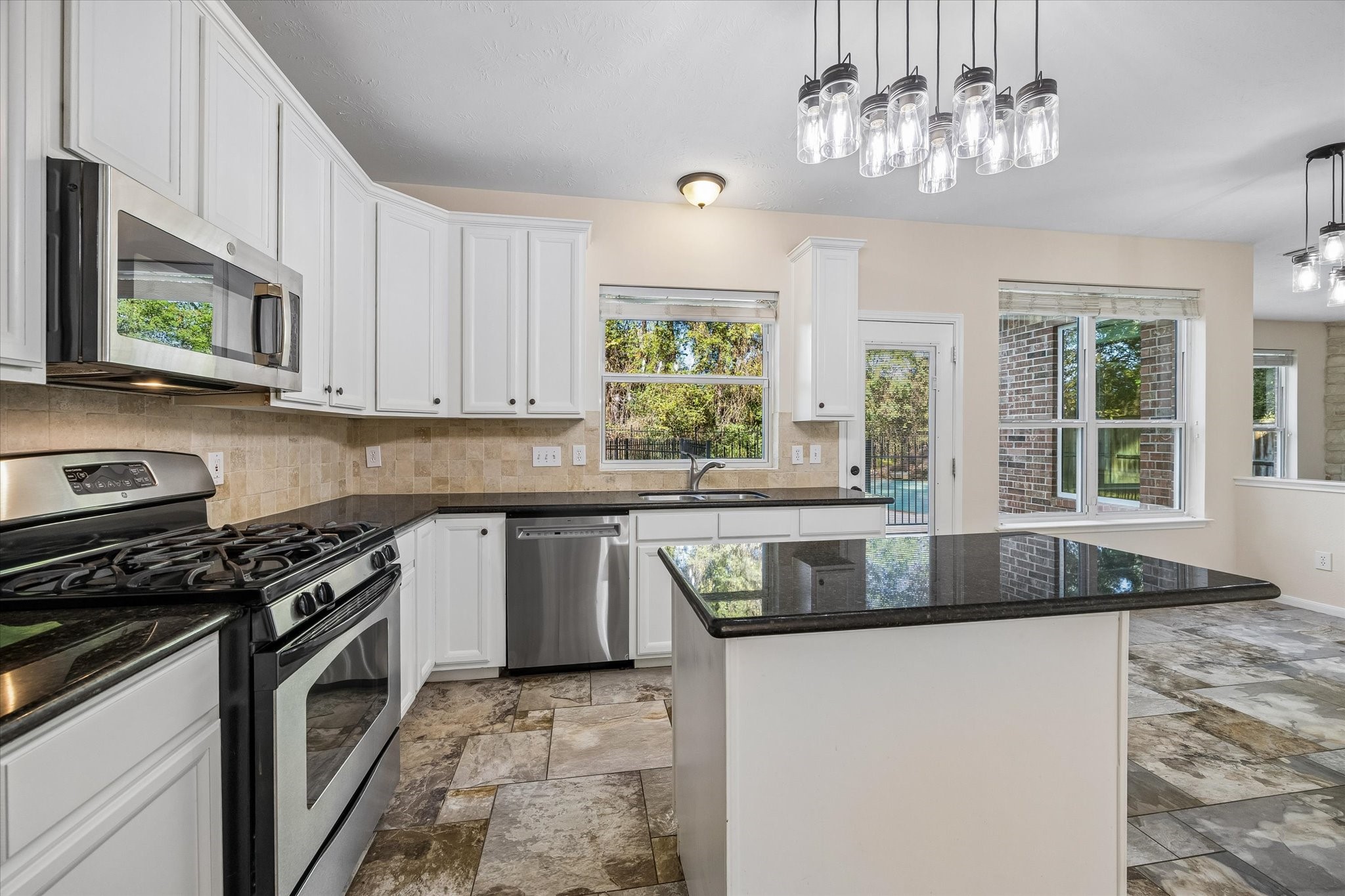 The kitchen features a double-basin sink positioned beneath a window overlooking the backyard, bringing in natural light and beautiful outdoor views. Don't miss the huge pantry!