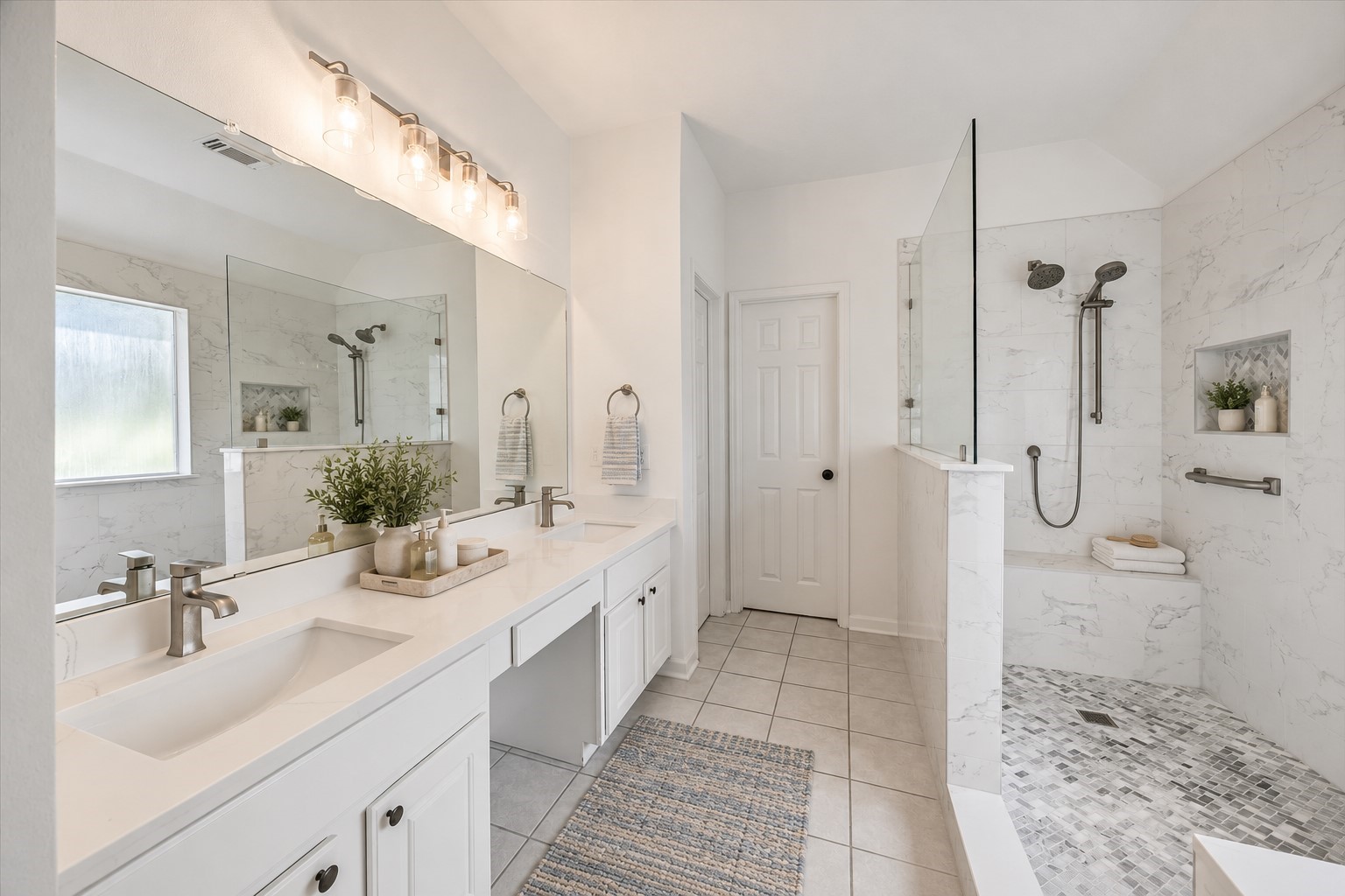 The spacious primary en-suite bathroom has been completely renovated. It features a modern feel with a dual-sink vanity, sleek countertops, and oversized mirrors, creating a clean and polished space. Virtually staged with accessories.