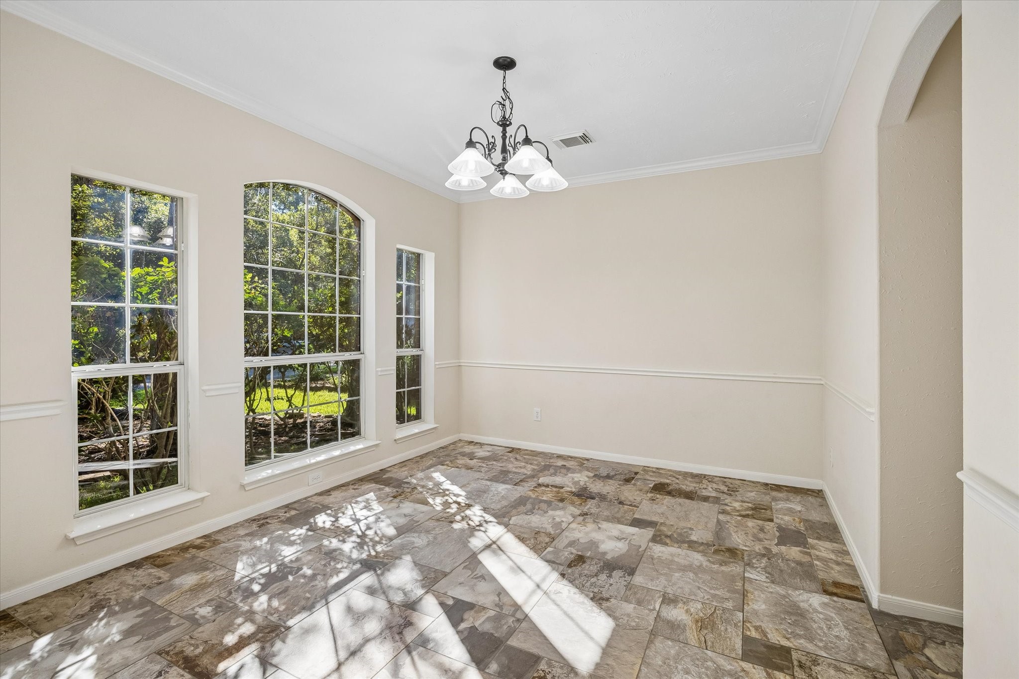 Elegant formal dining room featuring beautiful arched windows and decorative wall molding. A timeless space perfect for hosting memorable dinners and gathering with family and friends.