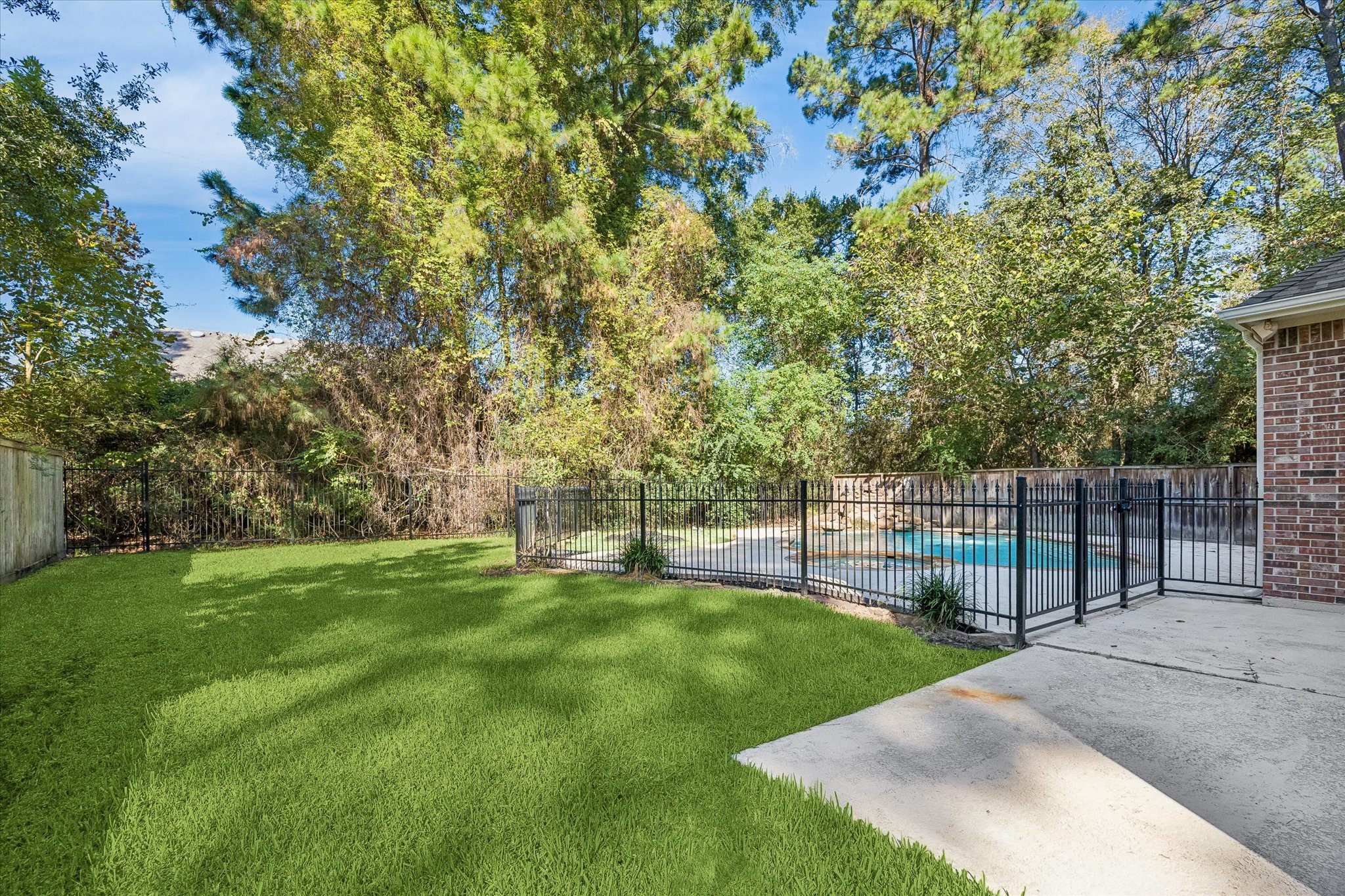 The backyard offers additional green space beyond the pool area, providing plenty of room for outdoor activities, gardening, or simply enjoying the spacious yard.