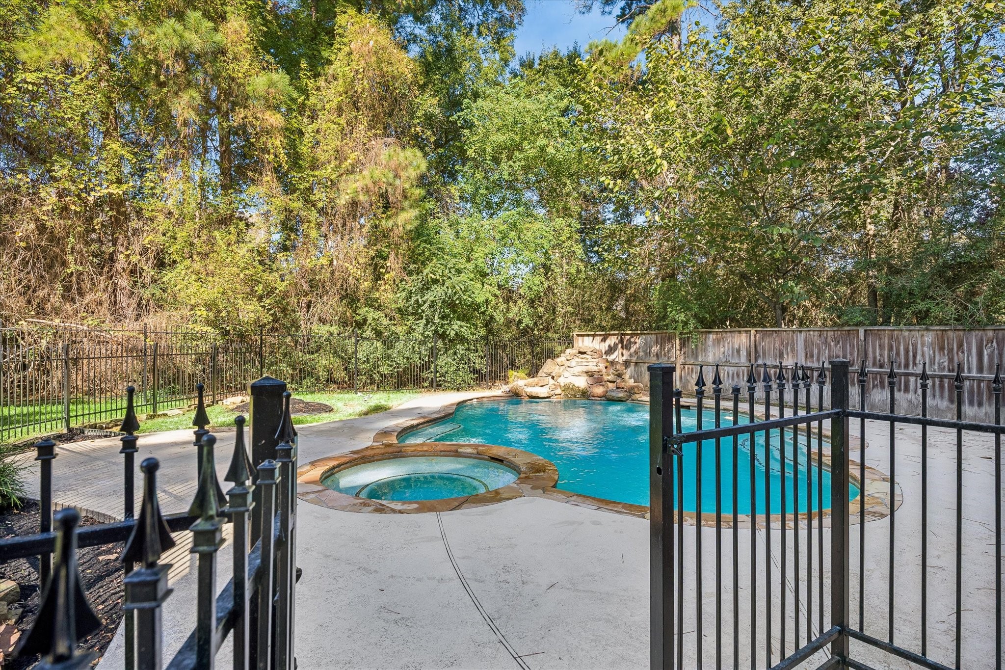 The fully fenced backyard offers added privacy, with a wrought-iron pool fence surrounding the sparkling pool and spa.