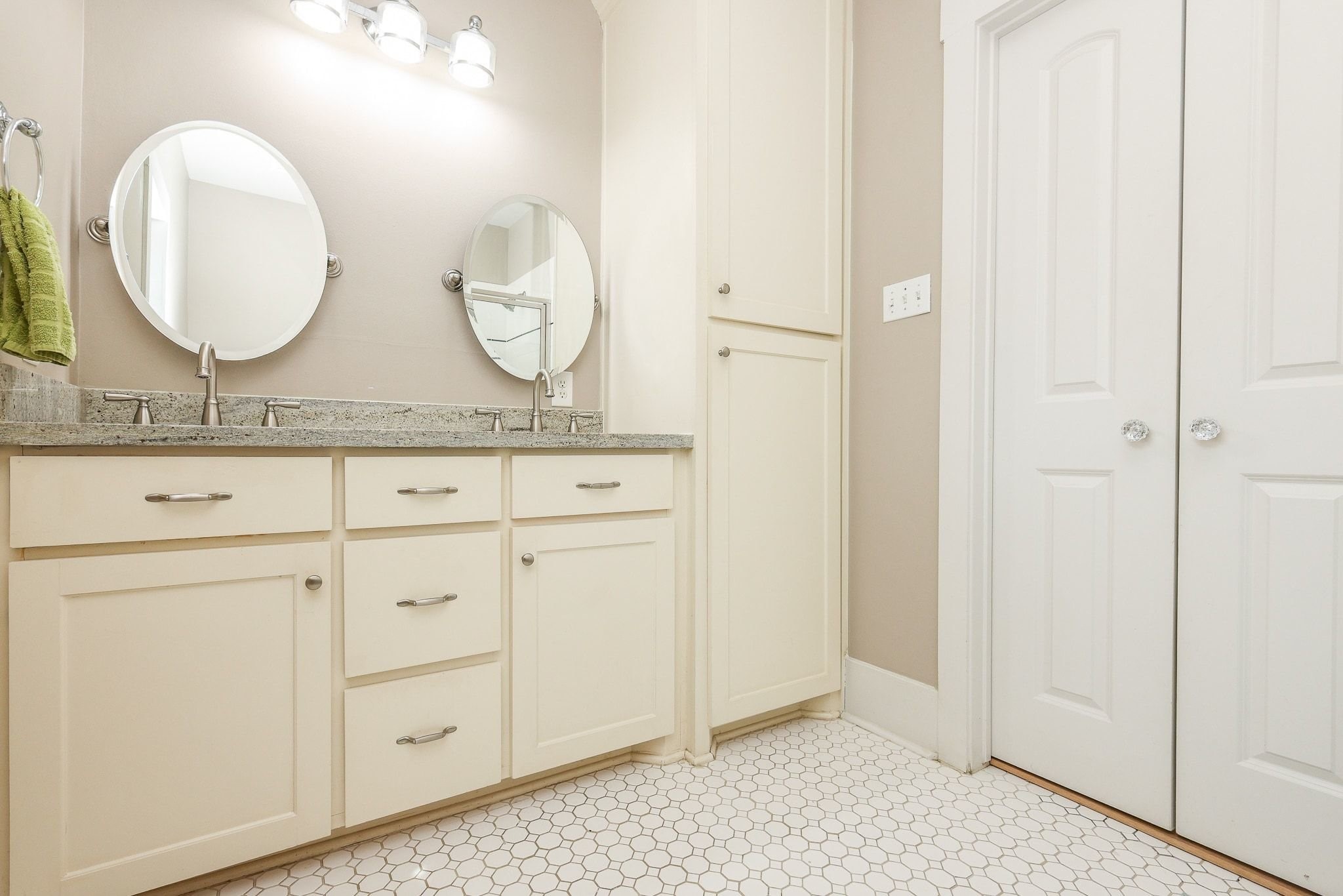 Bathroom with a double vanity with undermount sinks, a large mirror, and dual wall-mounted light fixtures.