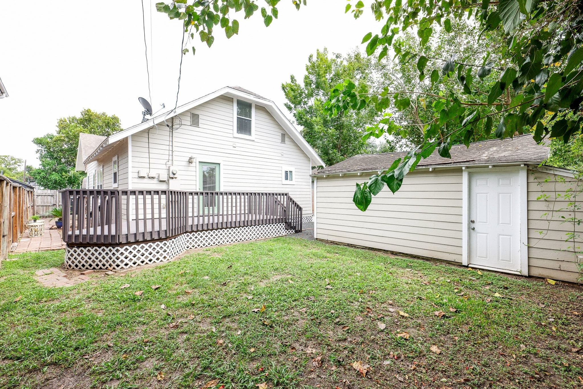 Fenced backyard with a spacious grassy lawn and wood deck.
