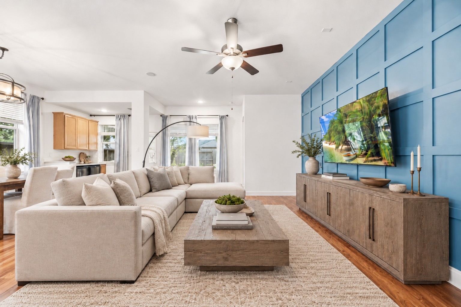 living area with a stylish blue accent wall, this cozy open layout flows into a bright dining and kitchen space, perfect for entertaining. Virtually Staged