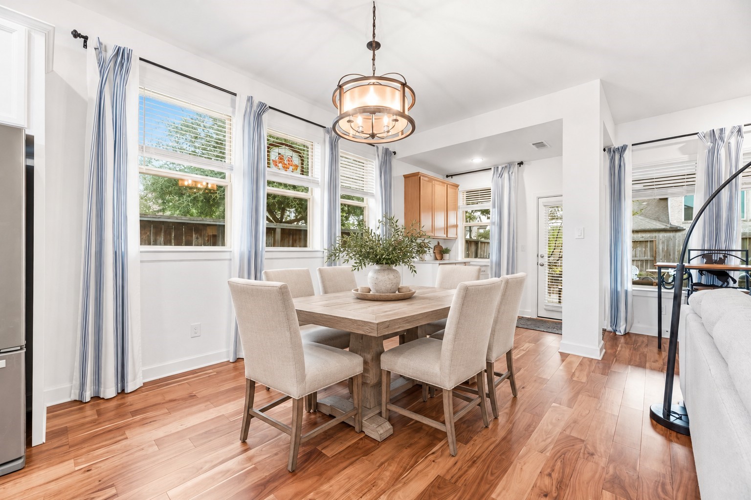 Bright and inviting breakfast/dining area features rich hardwood floors, abundant natural light from large windows, seamlessly connected to a cozy kitchen space. Virtually Staged
